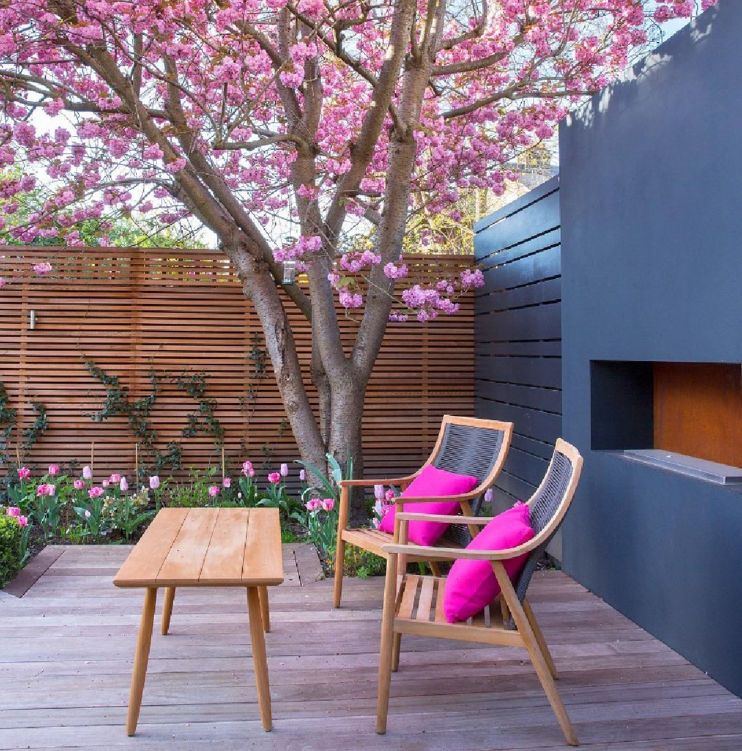 Farrow & Ball Railings on an outdoor fireplace wall in a lovely garden with pink flowering tree - @mariannemajerus. #farrowandballrailings