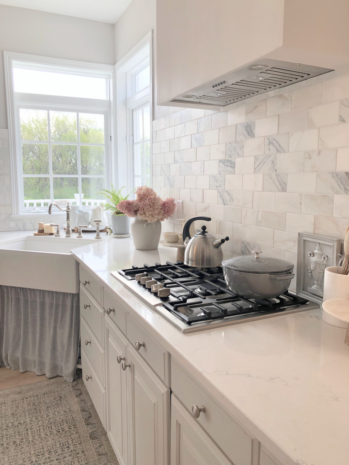 Hello Lovely's light grey and white modern French kitchen with Muse quartz, farm sink, Calacatta marble backsplash and Staub French oven.