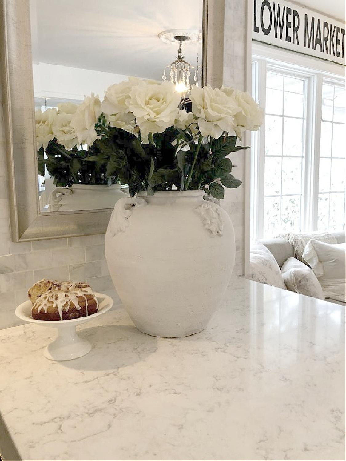 White terracotta urn with white roses in modern French kitchen with Minuet quartz countertops (Viatera) - Hello Lovely Studio. #minuetquartz #whitequartzcountertop