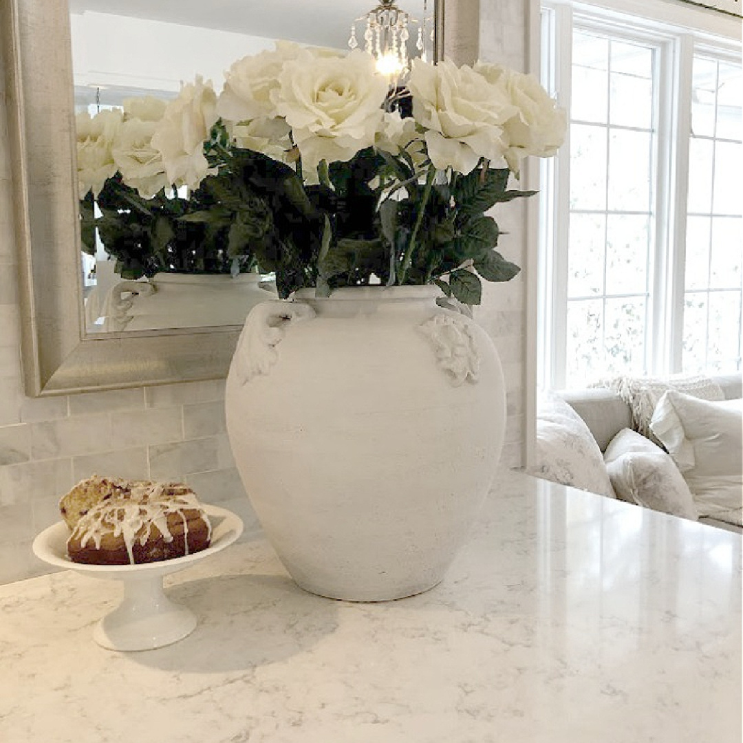 White terracotta urn with white roses in modern French kitchen with Minuet quartz countertops (Viatera) - Hello Lovely Studio. #minuetquartz #whitequartzcountertop