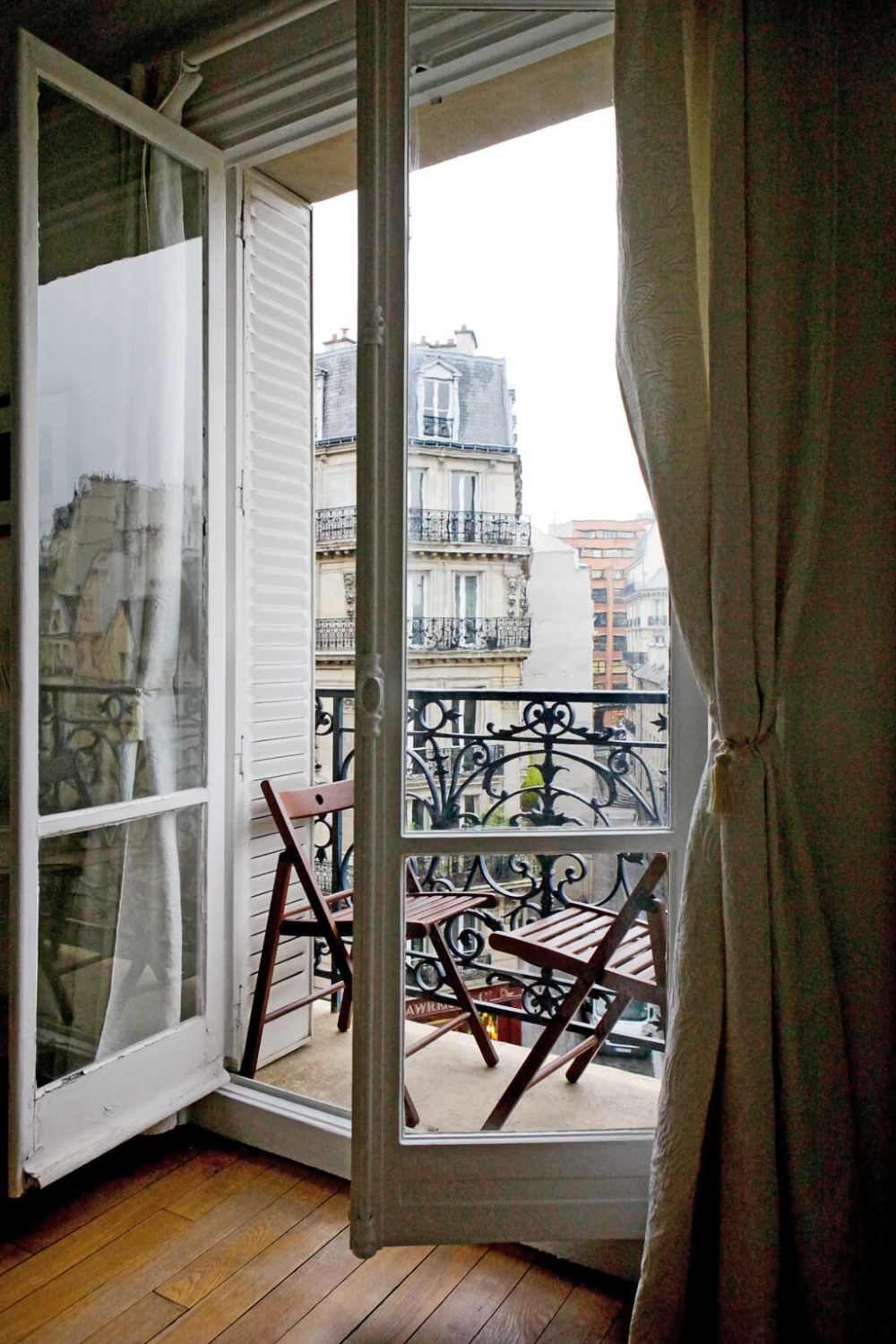 Balcony with French doors and view of Hausmannian buildings in a Paris apartment near Notre Dame - Hello Lovely Studio.