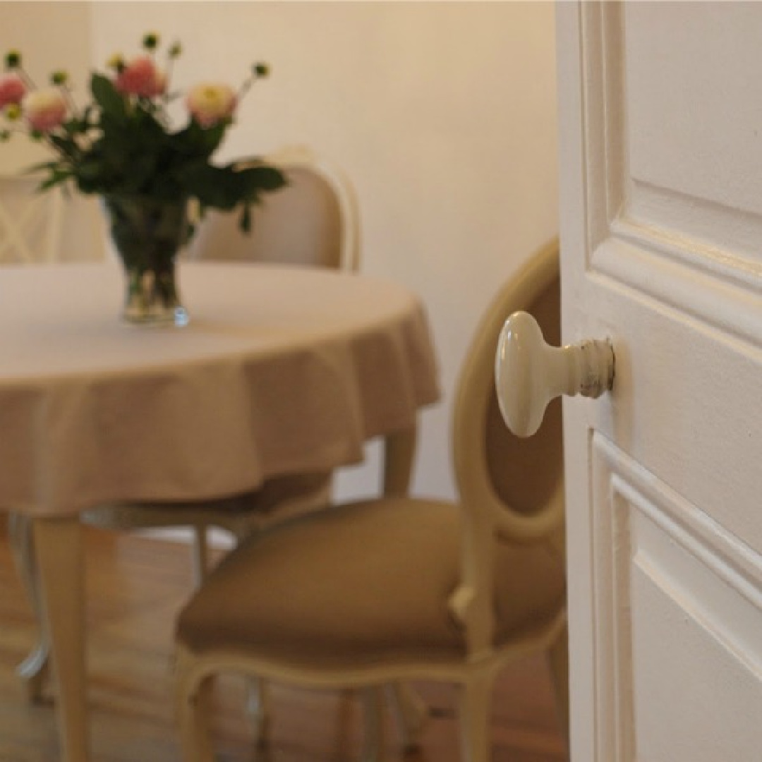 Detail of enamel oval hardware on white painted door to dining area in a Paris apartment near Notre Dame - Hello Lovely Studio.