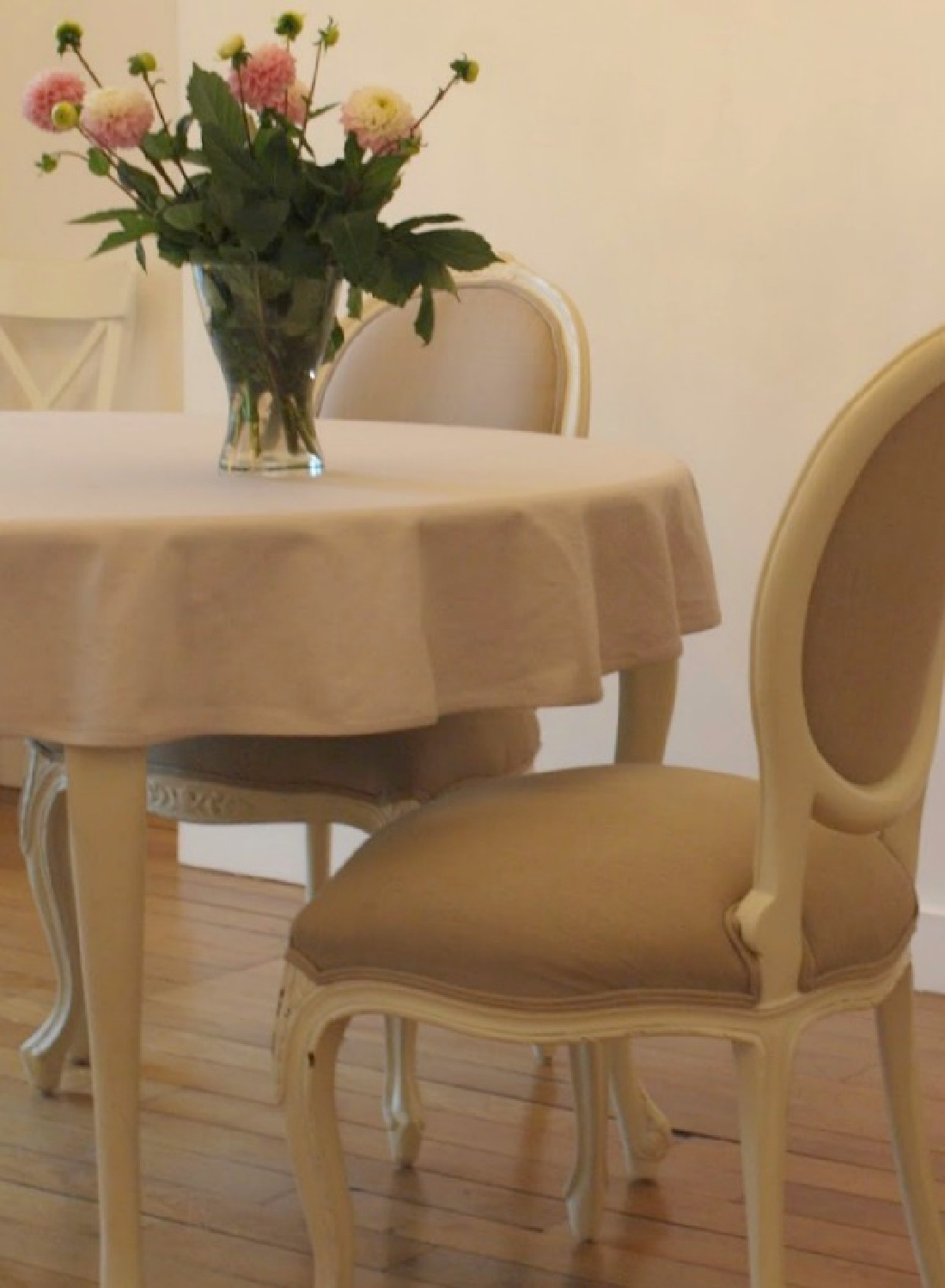 Oval back Louis French dining chairs around a round table with ranuculus in vase in a Paris apartment near Notre Dame - Hello Lovely Studio.