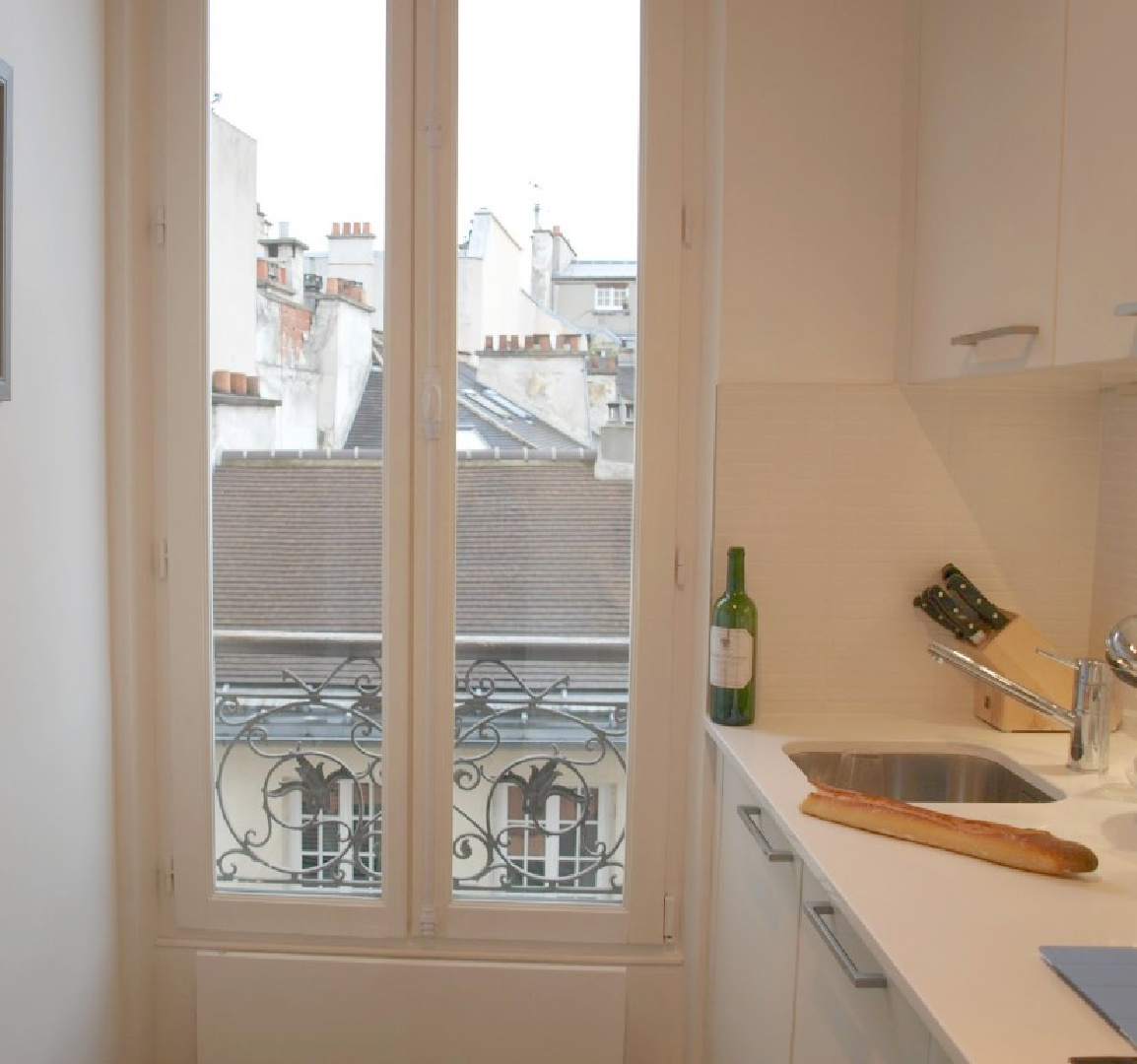Modern Paris apartment white kitchen with windows and balcony - Hello Lovely Studio.