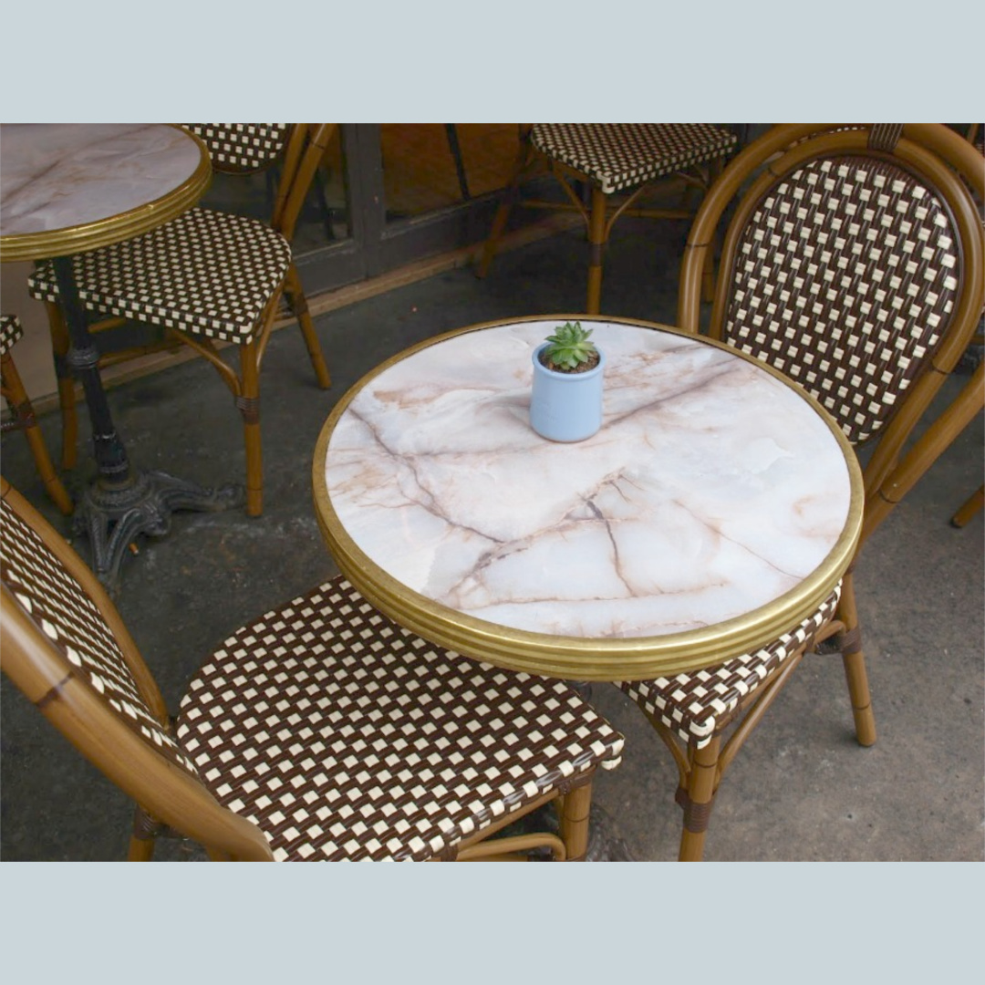 A cafe in Paris with classic brown patterned bistro chairs at round marble tables - Hello Lovely Studio.
