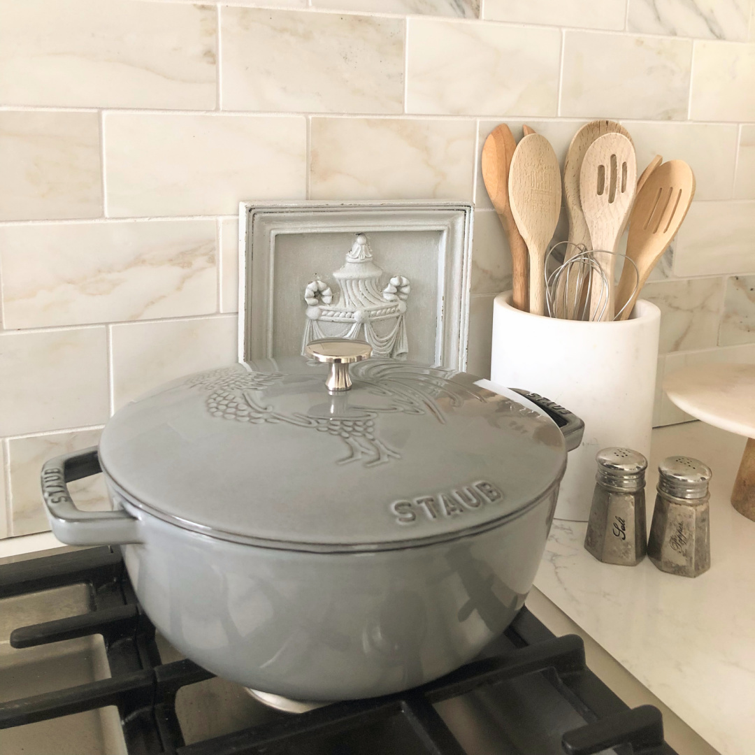 Staub French Oven with Rooster (Graphite Grey) on cooktop with Calacatta marble backsplash and Muse quartz in our modern French kitchen - Hello Lovely Studio. #staub #modernfrench