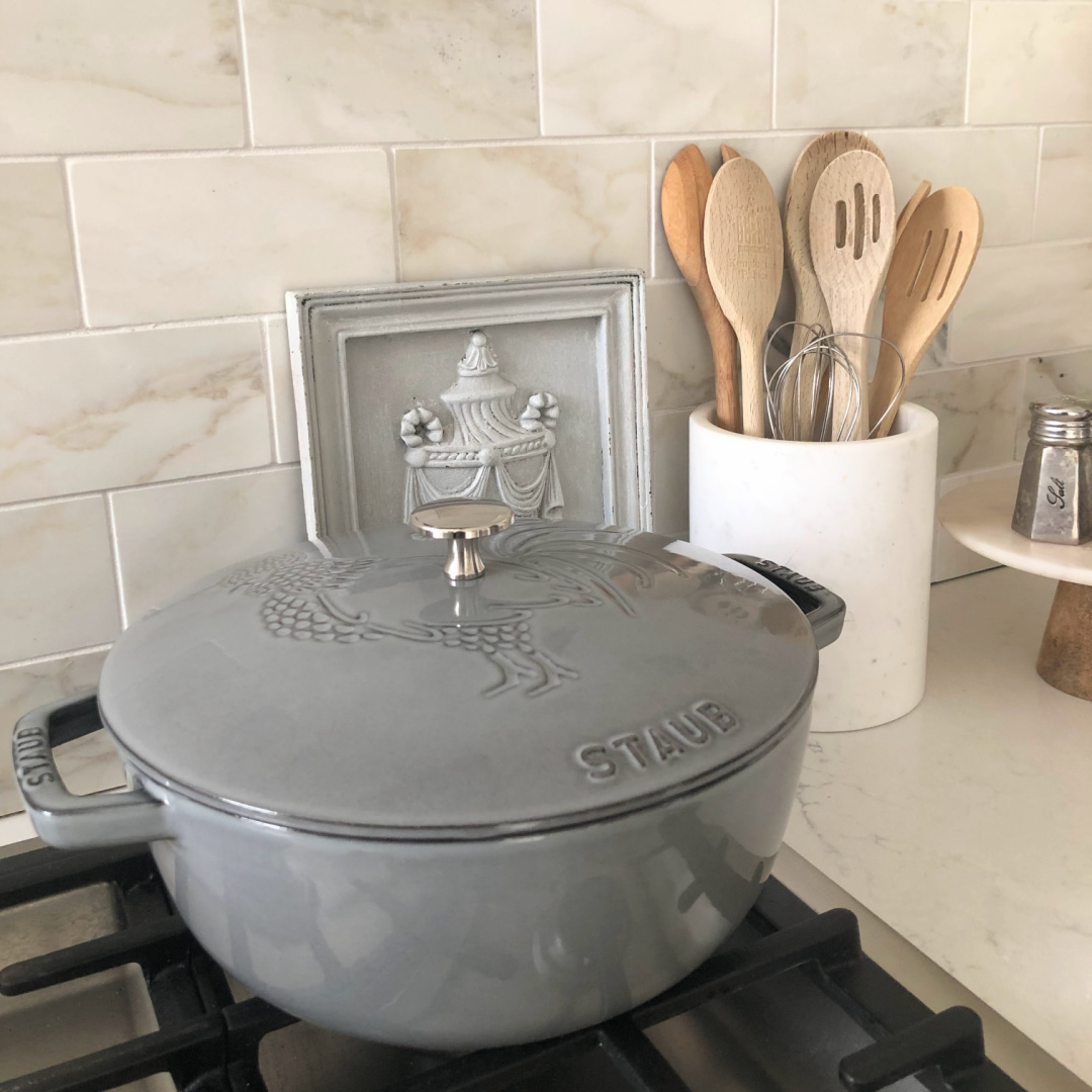 Hello Lovely's light grey and white modern French kitchen with Muse quartz, farm sink, Calacatta marble backsplash and Staub French oven. #modernfrench #staub #dutchoven