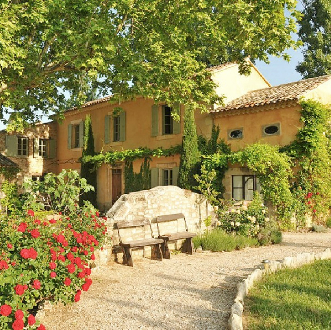 Beautiful French farmhouse exterior with yellow stucco and French blue shutters. Provence vacation rental Bonnieux Villa from Your Haven in Paris with lush gardens, romantic Old World rustic elegance.