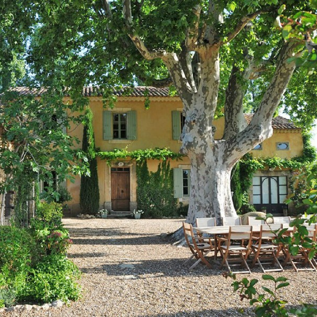 Beautiful French farmhouse exterior with yellow stucco and French blue shutters. Provence vacation rental Bonnieux Villa from Your Haven in Paris with lush gardens, romantic Old World rustic elegance.