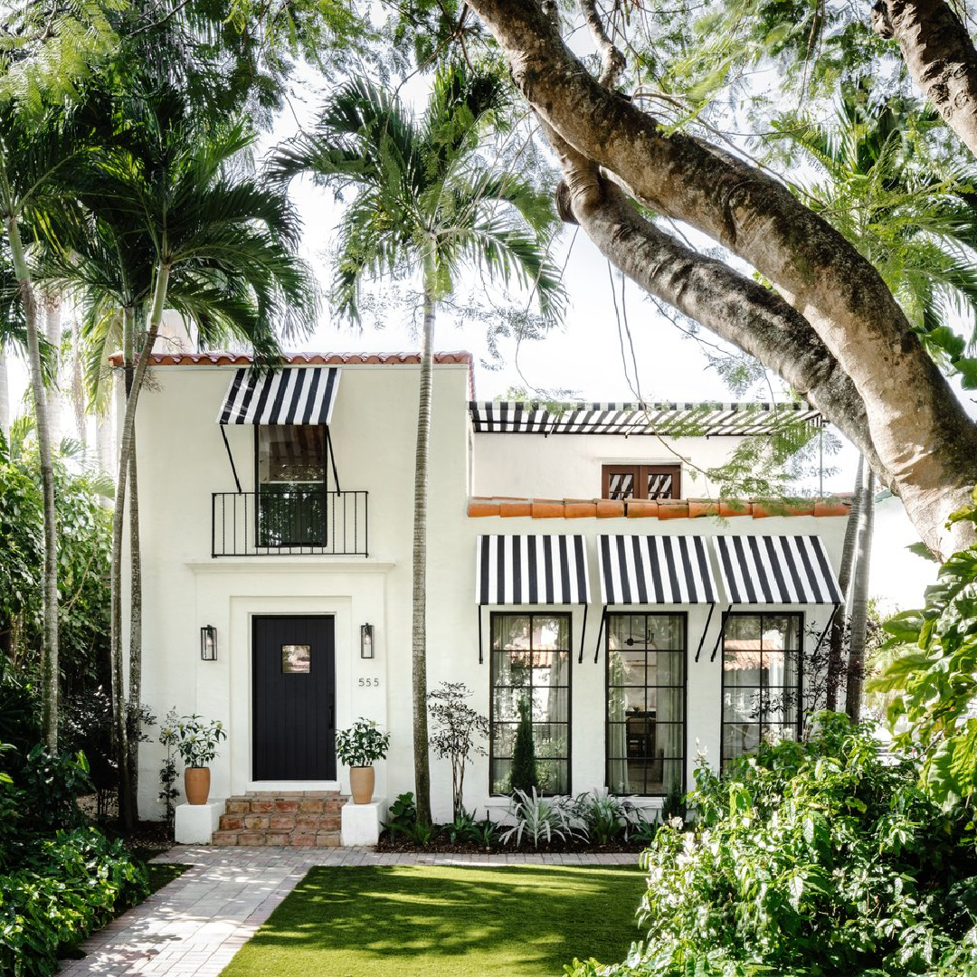 Charming Spanish bungalow facade in Coral Gables with black and white stripe awnings - @calimiahome.