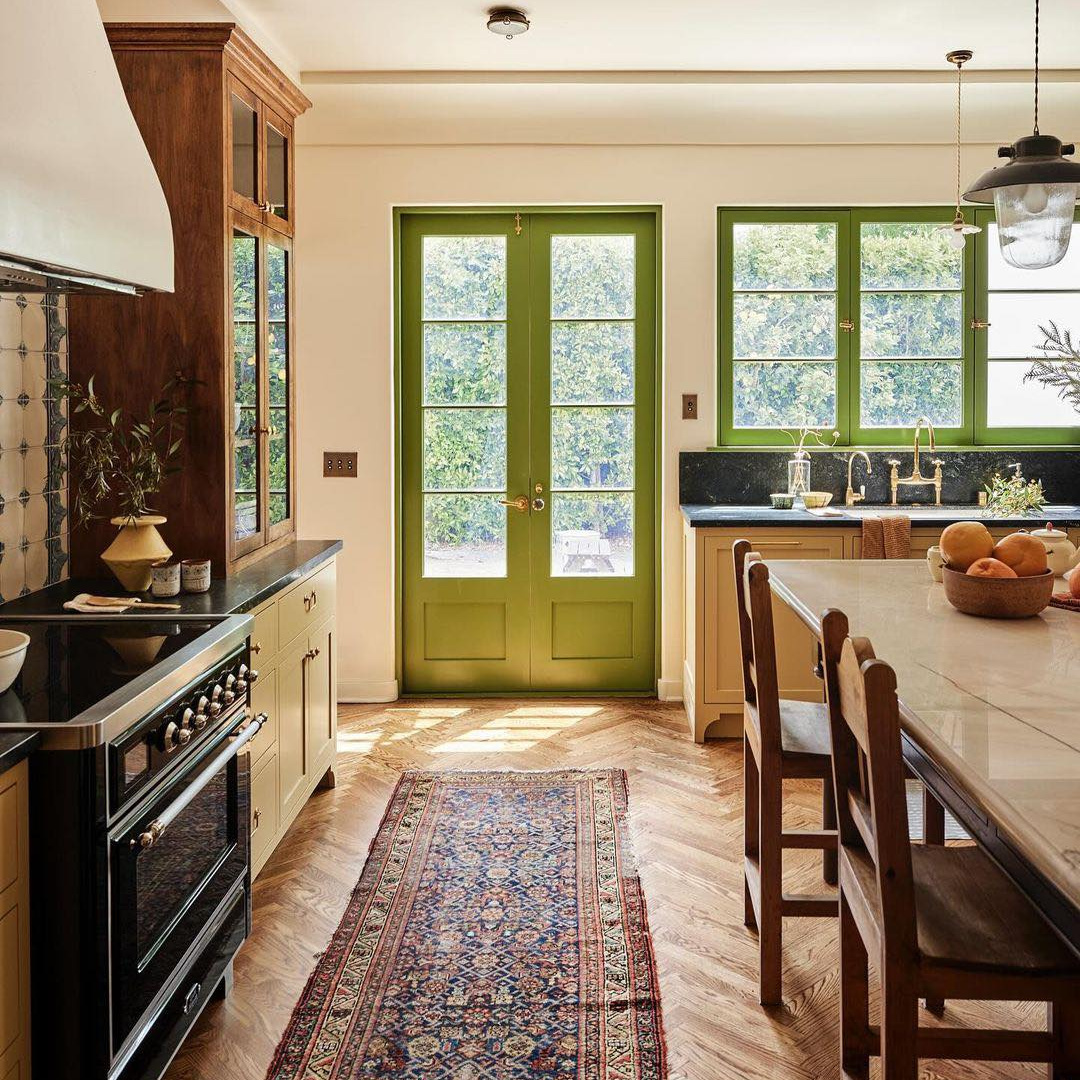 Bespoke kitchen with English country charm, bold citrine green doors and trim, and luxe range - design by Jamie Haller in House and Garden.