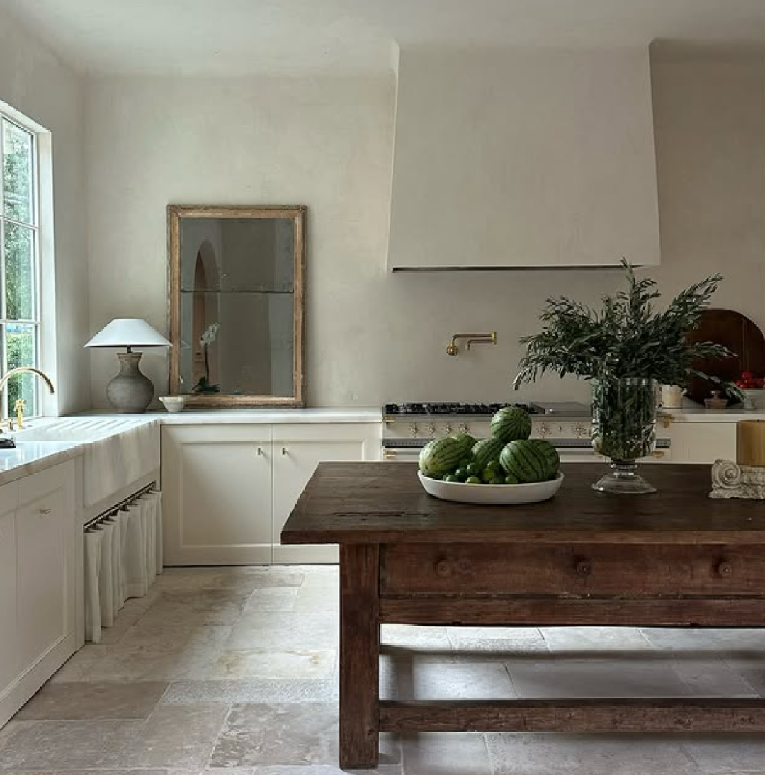 Jill Egan Interiors designed modern Belgian kitchen with plaster walls, stone floor tiles, and antiques.