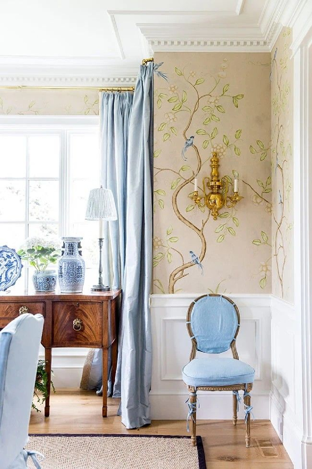 Chinoiserie wallpaper above wainscot in a dining room with blue accents and French country chic.