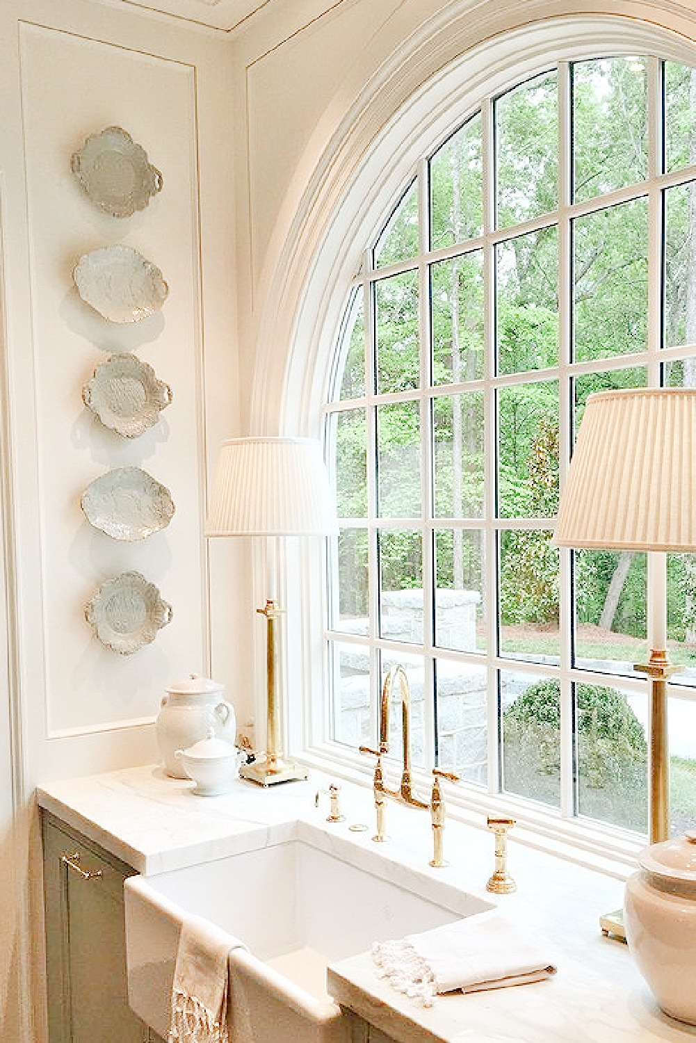 Breathtaking timeless designer showhouse kitchen with arch window at farm sink, F&B Light Blue cabinets, and antique platters hung on wall - Lauren DeLoach Interiors & Matthew Quinn Design.