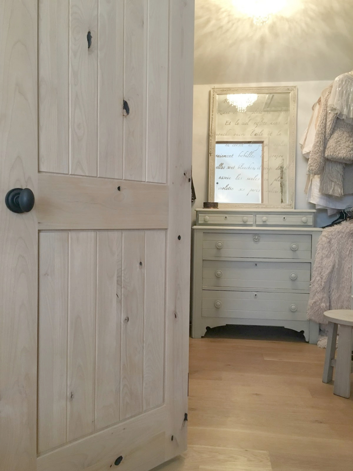 Hello Lovely's "her" walk-in closet with white oak floor, alder door, and antique dresser with mirror.