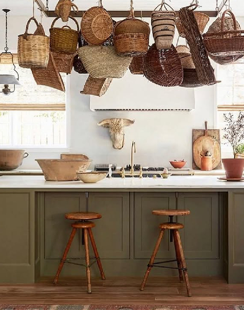 Shannon Bowers designed green gray kitchen in Milieu Showhouse 2020 with baskets hanging over island.
