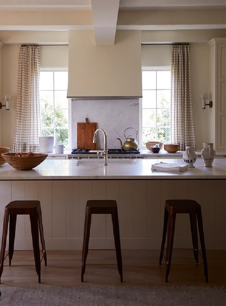 Shannon Bowers designed kitchen with check patterned curtains flanking range.