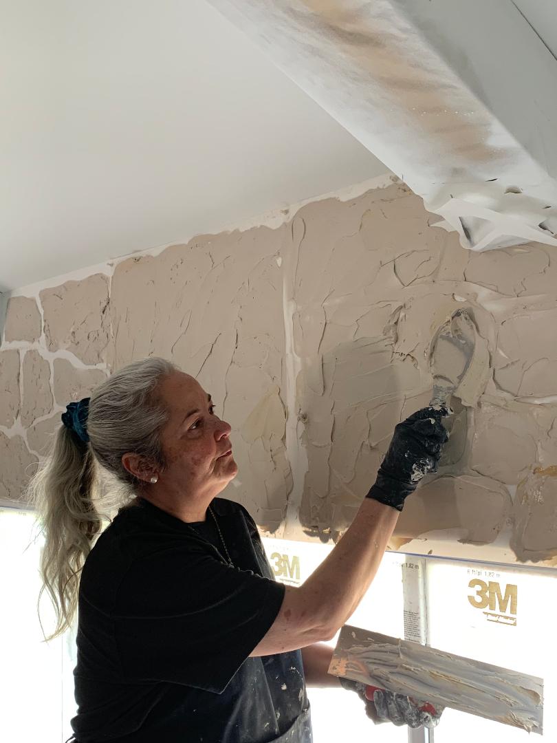 During the process of DIYer Rosalia creating a stone wall with The Detalles stone wall stencil kit.