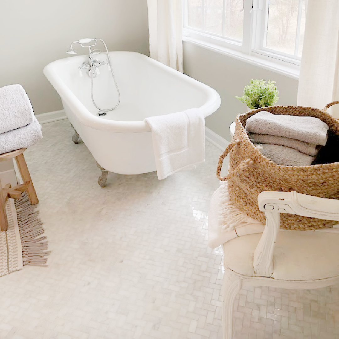 Hello Lovely's carrera marble herringbone mosaic tiled bathroom with clawfoot tub.