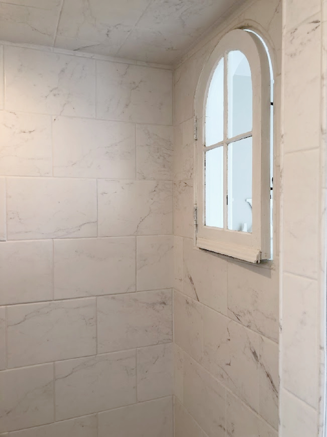 Hello Lovely's bathroom shower with salvaged arched window.