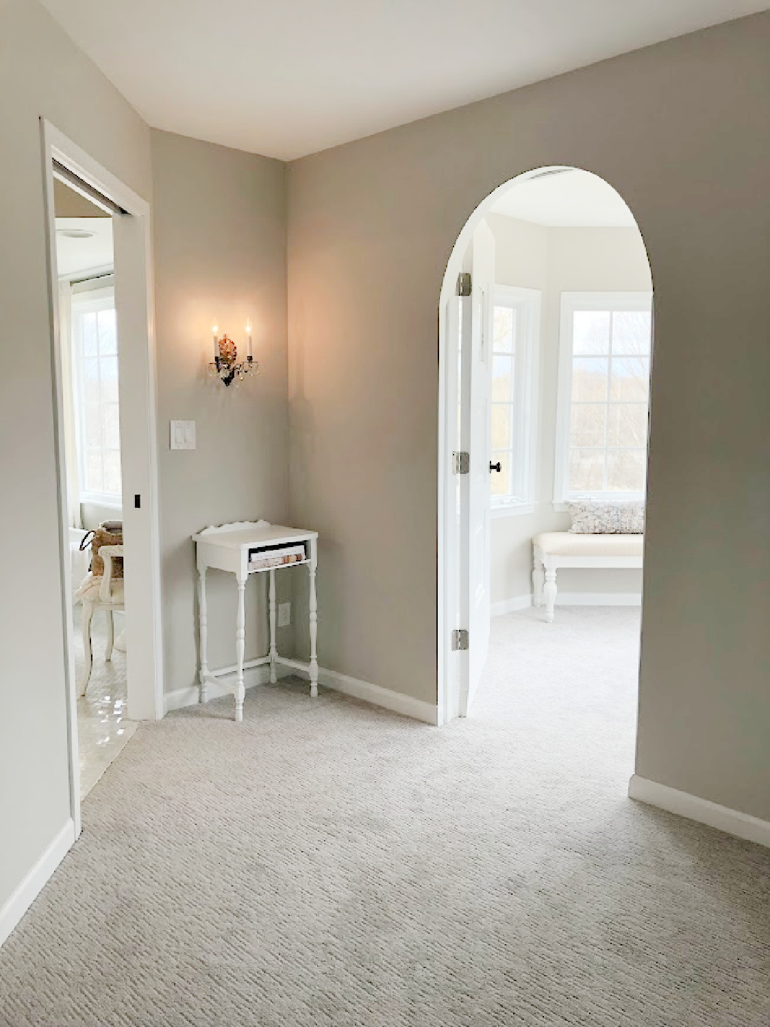 Hello Lovely's renovated bedroom with sitting area and arch doorway. Paint color is SW Agreeable Gray.