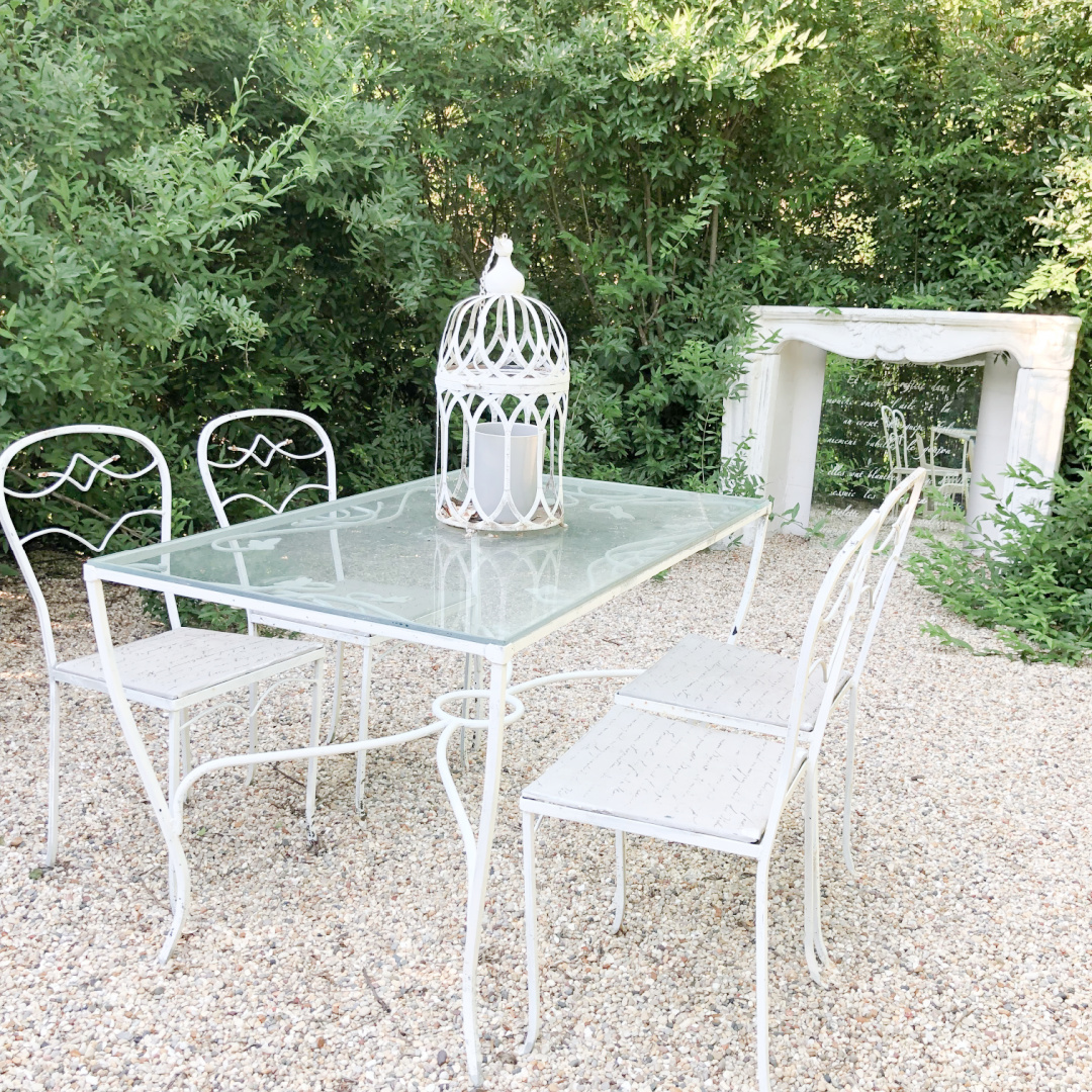 Hello Lovely's French country courtyard is a secret garden hedged with stone fireplace surround and vintage dining set on pea gravel.