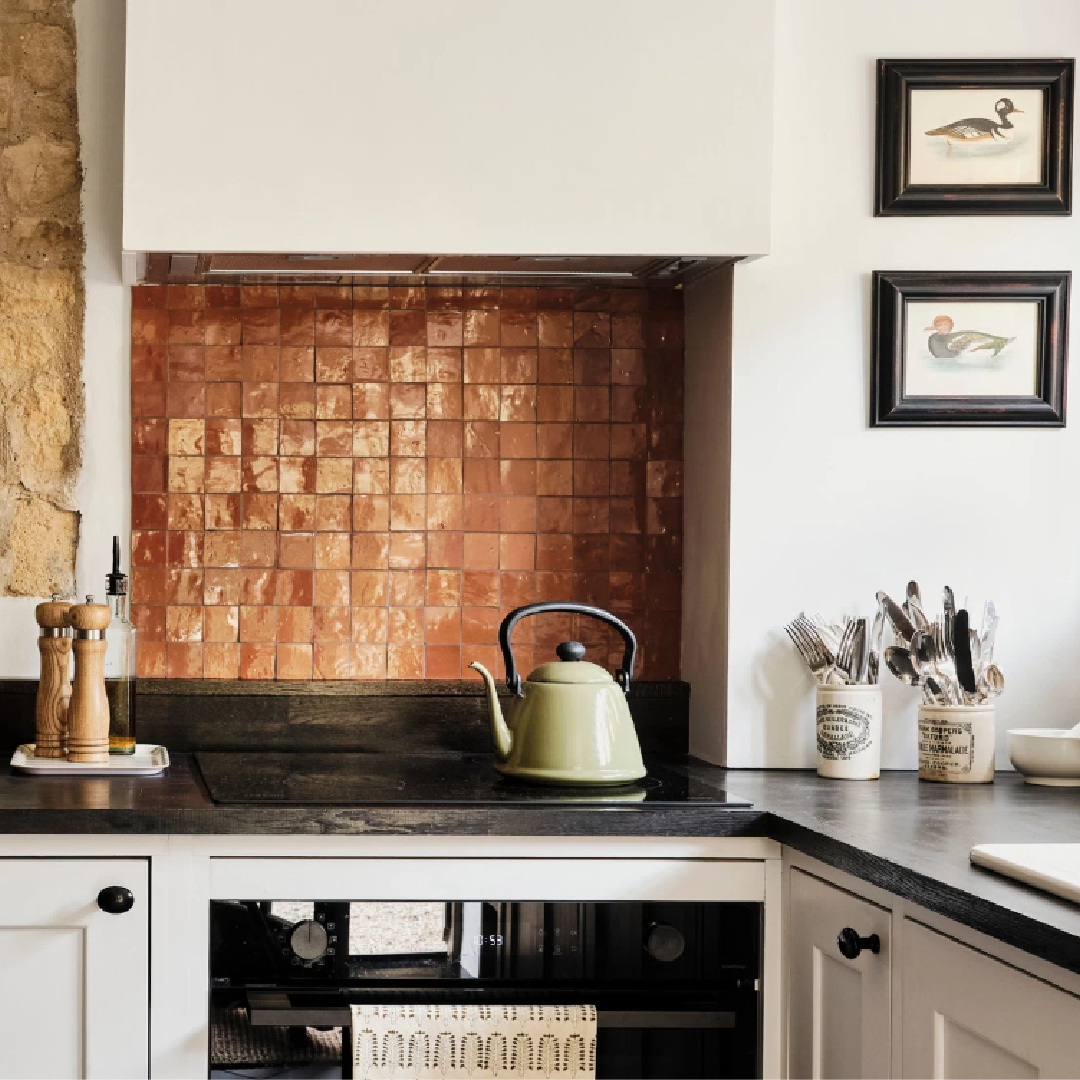 Terracotta tile backsplash in kitchen of Cotswolds stone cottage. Called Armada Cottage, it dates to 1489 with reimagined interiors by Beth Dadswell (Imperfect Interiors).