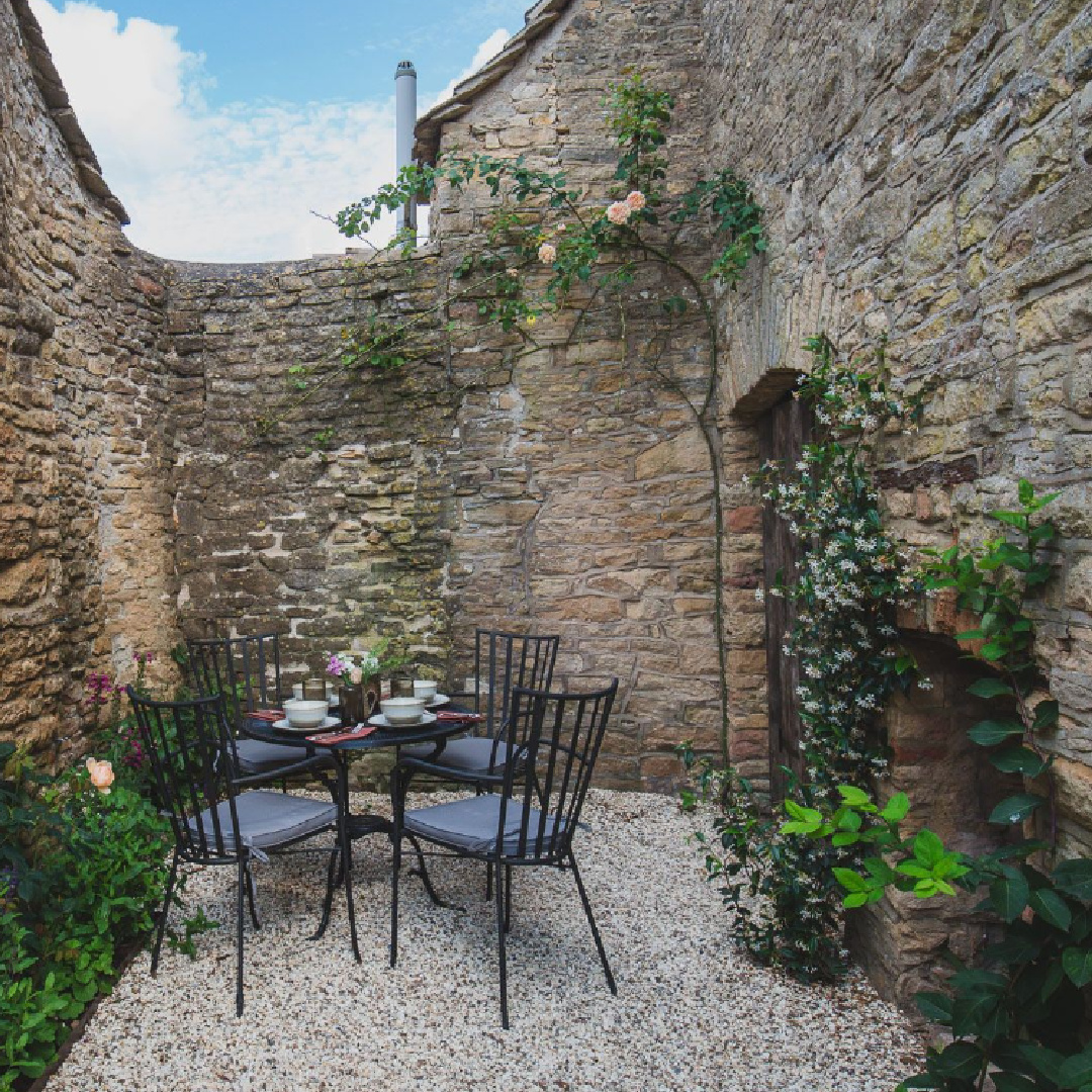 Charming dining area in courtyard of Cotswolds stone cottage called Armada Cottage. It dates to 1489 with reimagined interiors by Beth Dadswell (Imperfect Interiors).