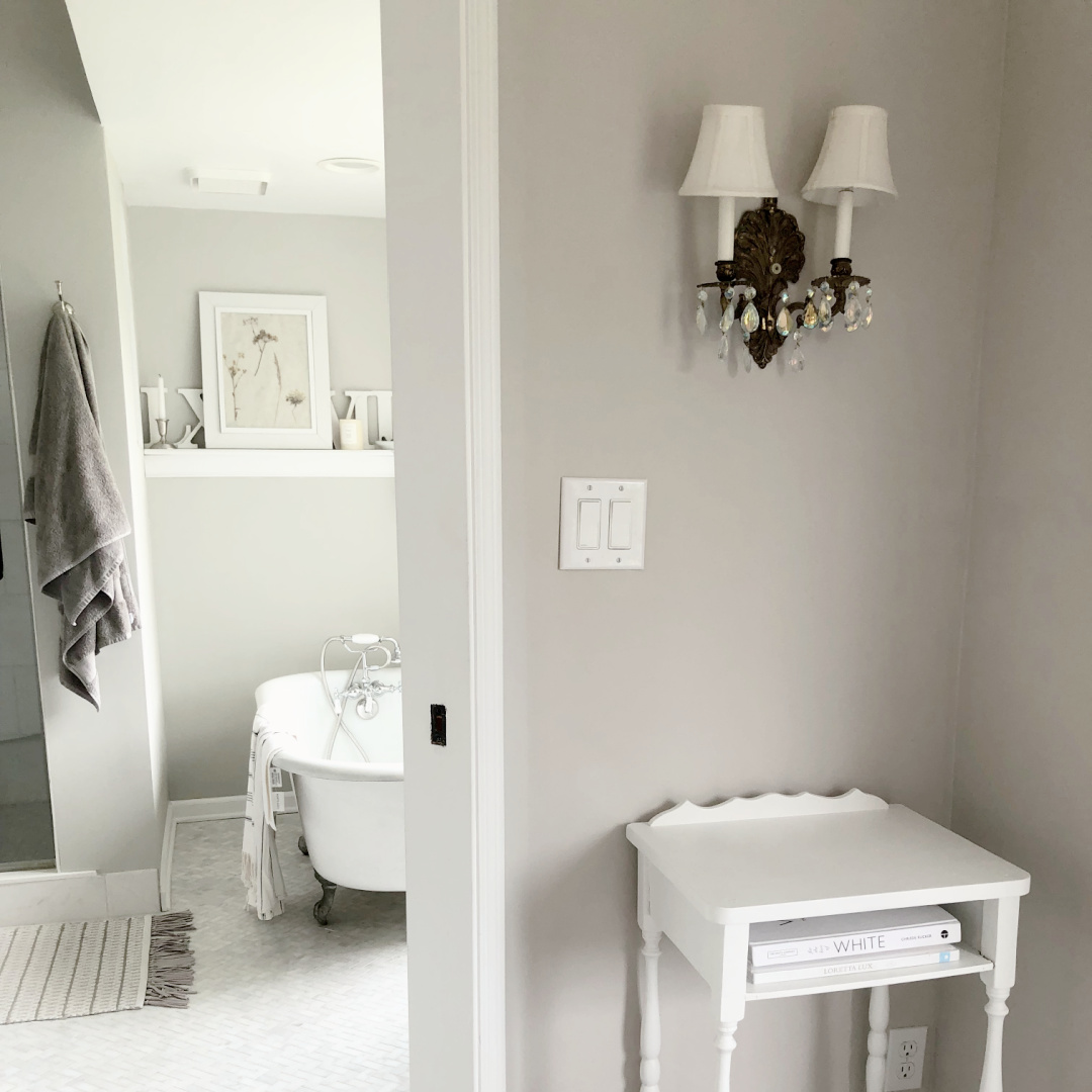 Hello Lovely's primary bedroom and bath with vintage lighting, clawfoot tub, and walls painted SW Agreeable Gray.