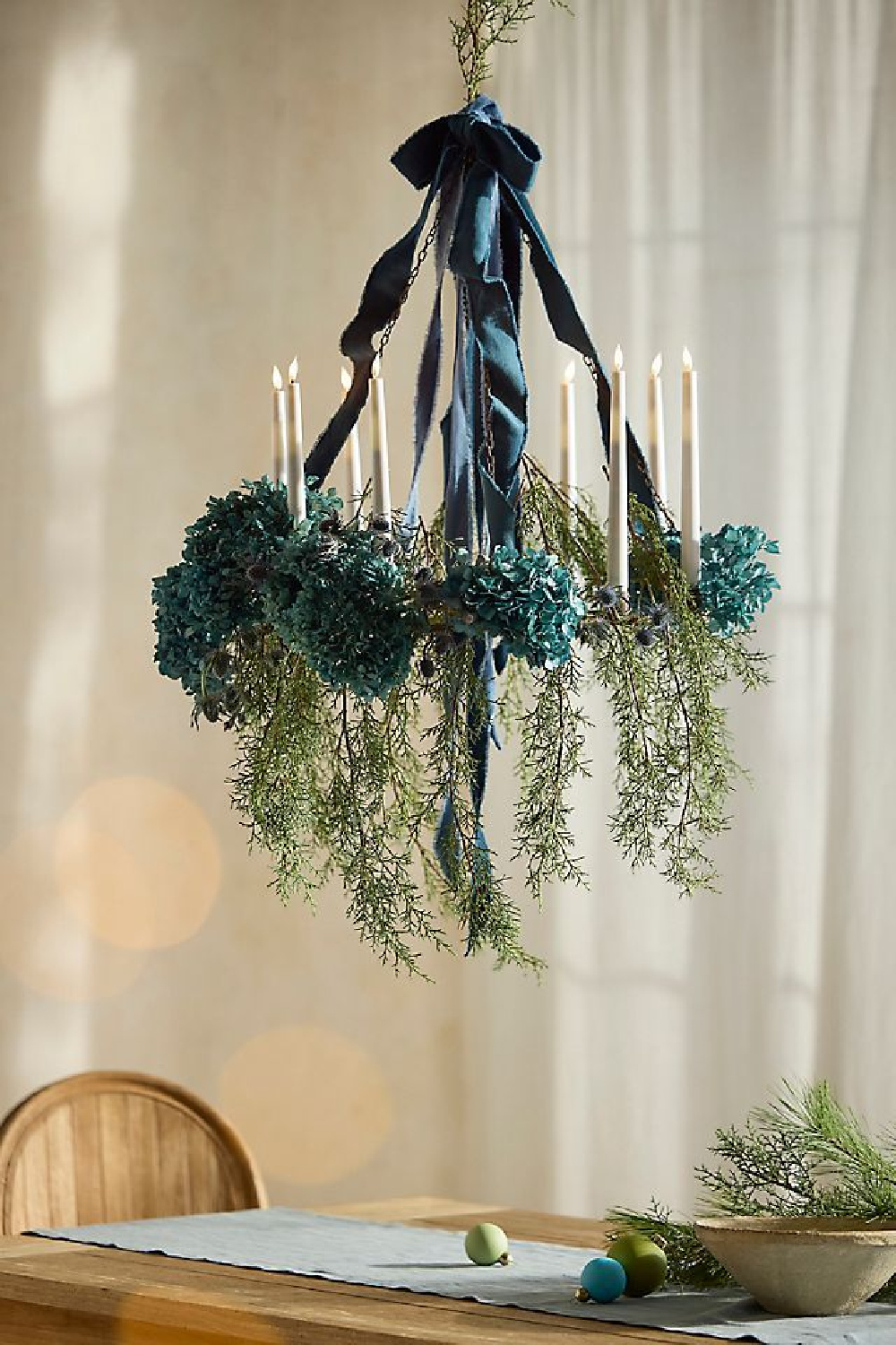 Beautiful holiday greenery and candle chandelier over dining table - Terrain. #holidaydecor #holidaygreenery
