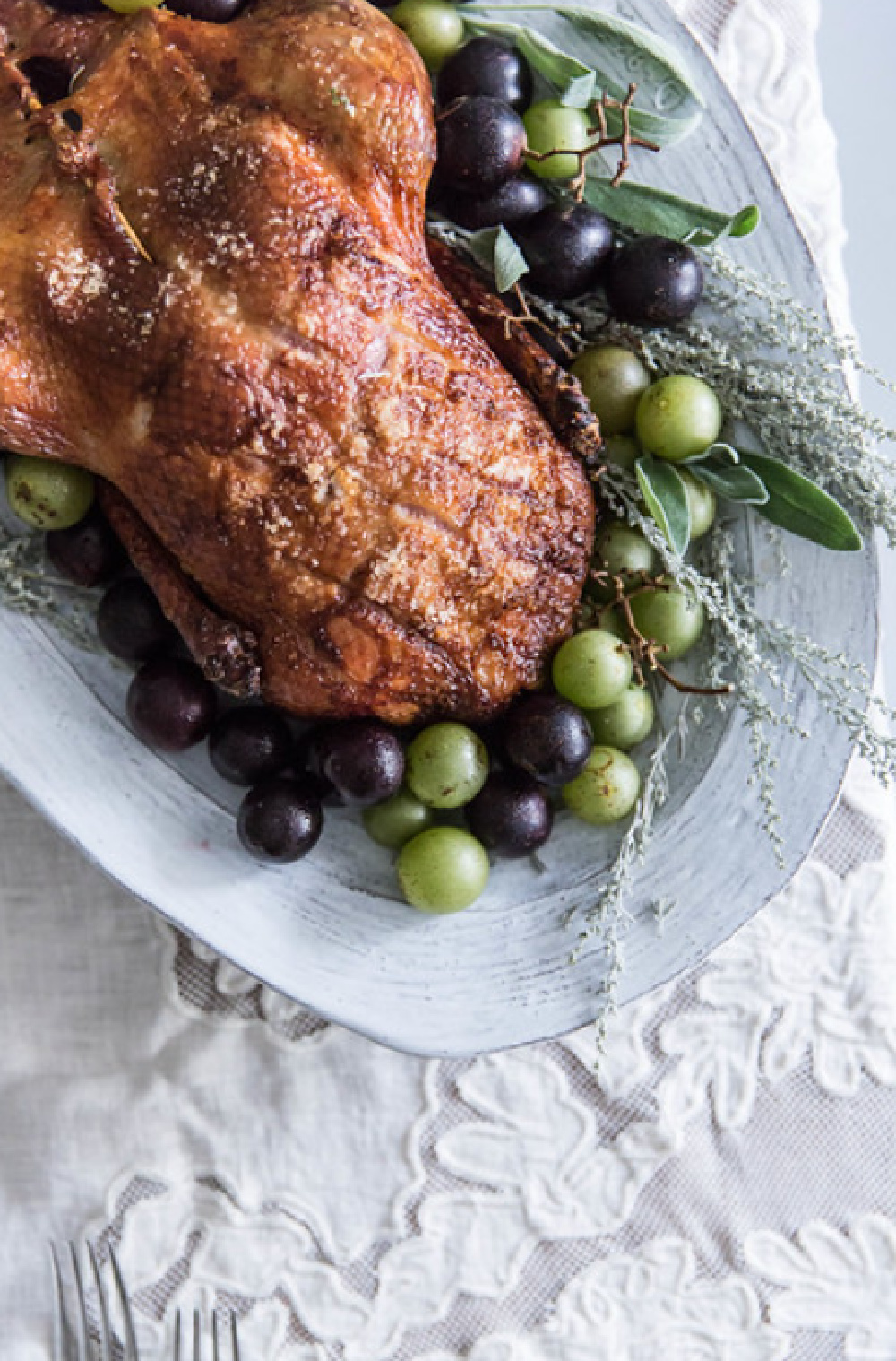 Gorgeous turkey with grapes and herbs on oval platter upon lace tablecloth - Beth Kirby (Local Milk).