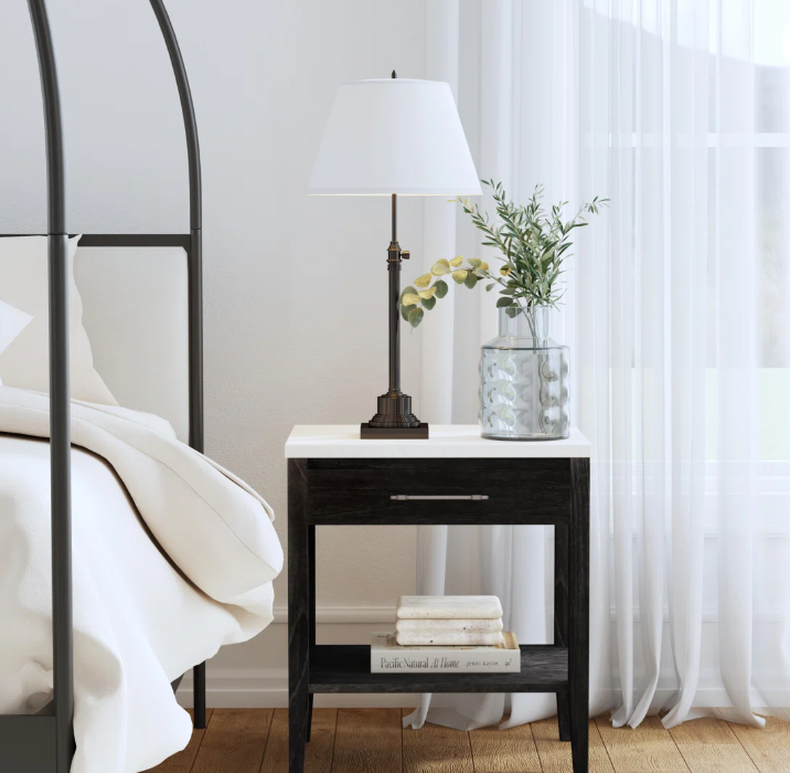 Black and white bedroom with black wood nightstand with white marble top and one drawer.