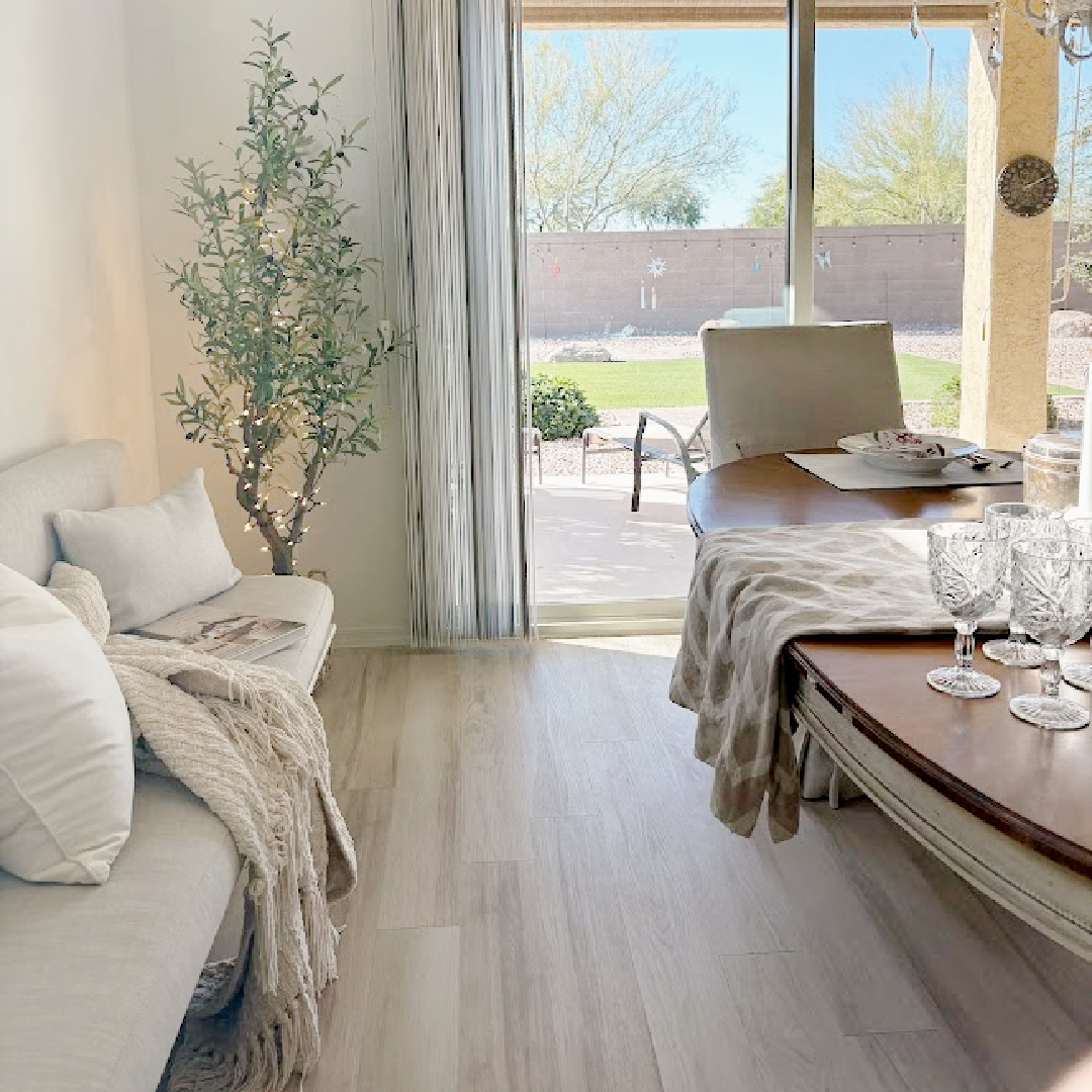 Banquette, olive tree, and oval classic dining table in Hello Lovely's snowbird sanctuary dining room with European country style.