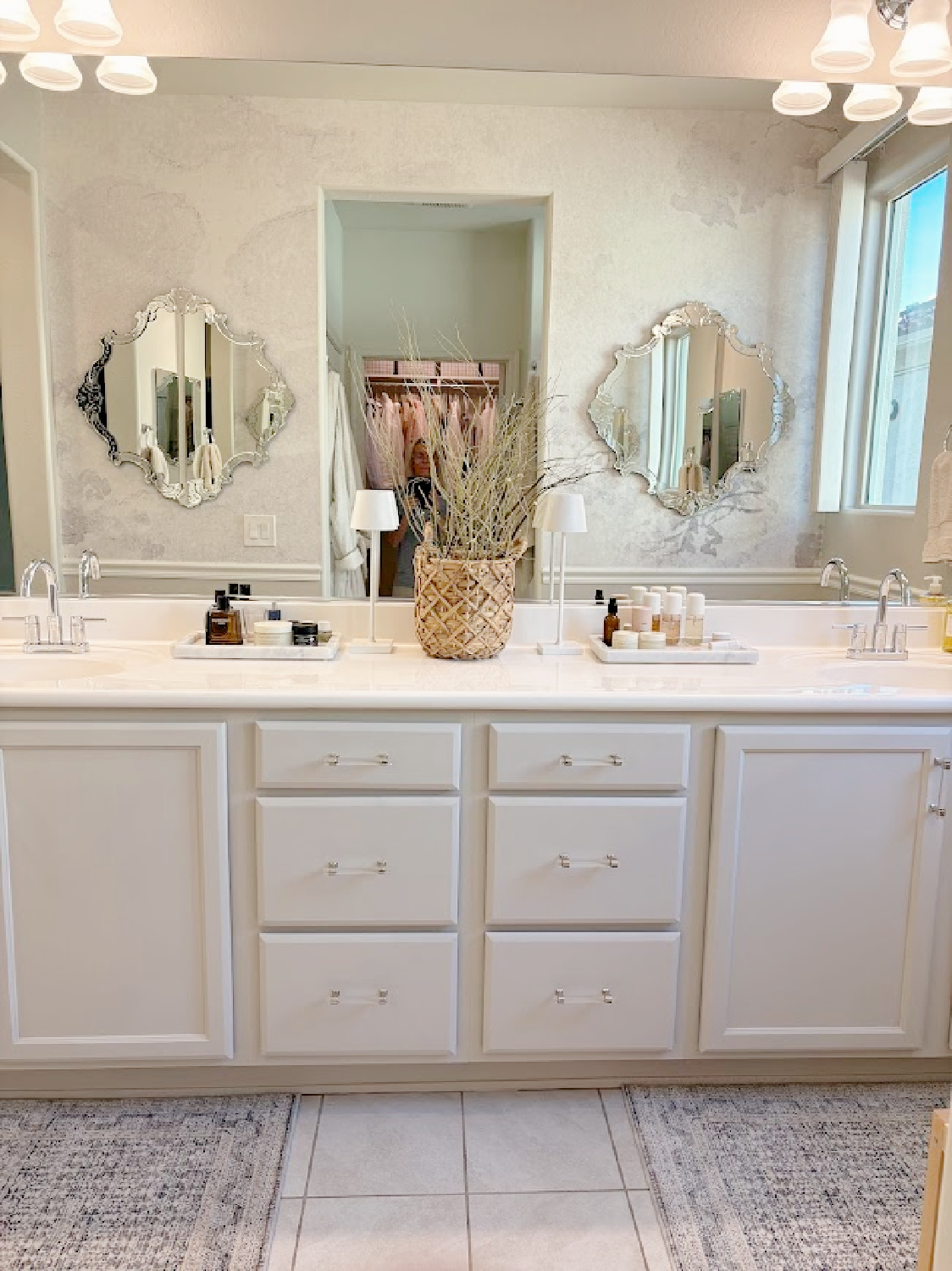 Our renovated bath at the snowbird Arizona house with SW Agreeable Gray painted vanity, lucite hardware, Venetian mirrors layered on a Photowall mural wallpaper, and rugs from Loloi x Amber Lewis - Hello Lovely Studio.
