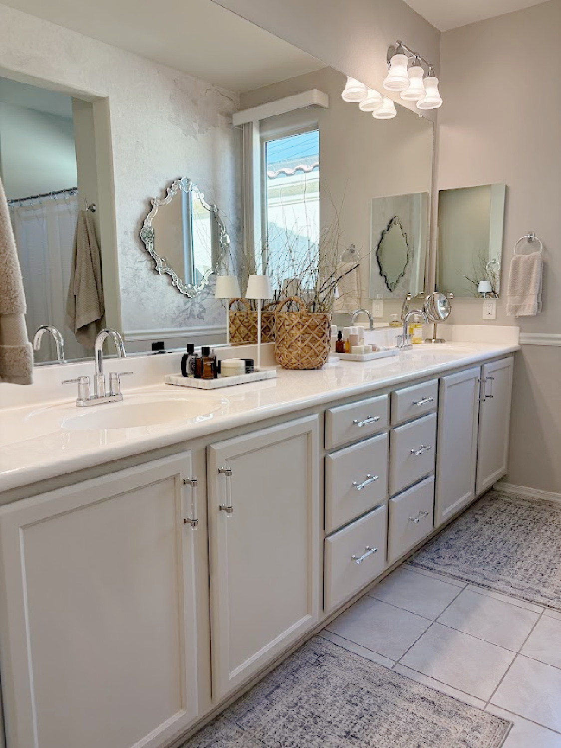 Our renovated bath at the snowbird Arizona house with SW Agreeable Gray painted vanity, lucite hardware, Venetian mirrors layered on a Photowall mural wallpaper, and rugs from Loloi x Amber Lewis - Hello Lovely Studio.