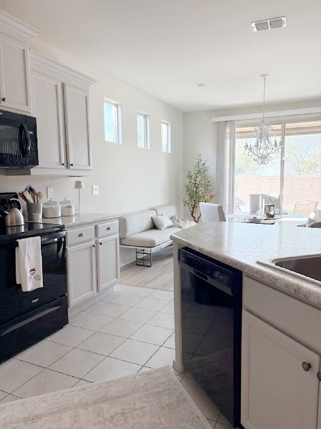I calmed our Arizona snowbird kitchen cabinets with Sherwin Williams Agreeable Gray, accent lighting, and a pretty rug to cover beige ceramic tile - Hello Lovely Studio.