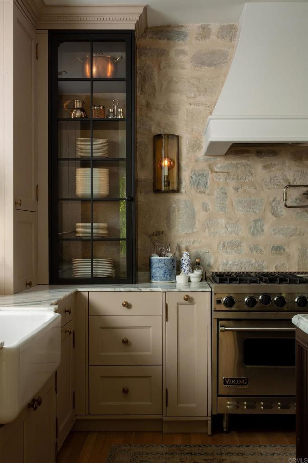 Rustic stone backsplash in Leslie Martin's black and limestone two tone kitchen in stunning traditional coastal home 5735 Dolphin in La Jolla, CA with interiors by M+M Interior Design. Offered by @nelsonbrothersrealestate