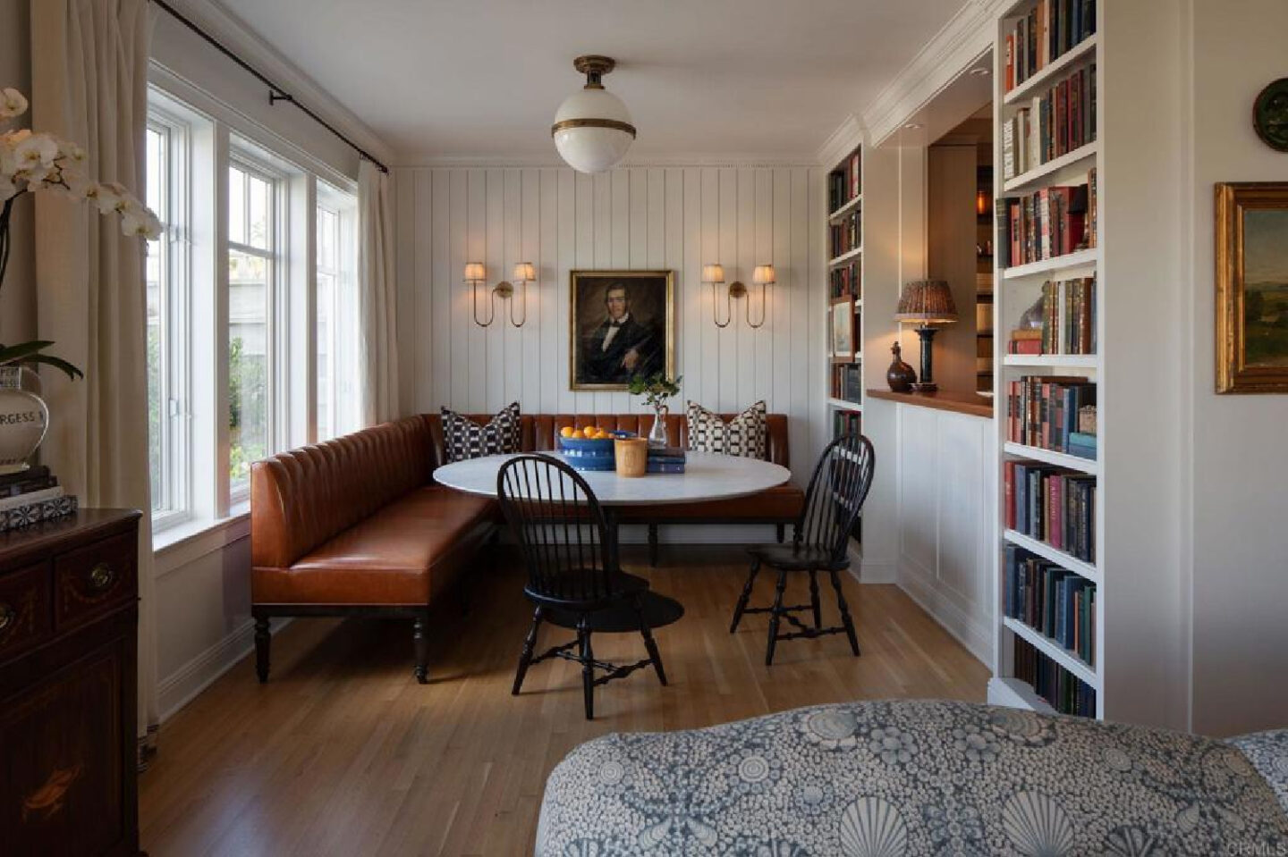 Small cozy dining with paneled walls and shelves in Leslie Martin's stunning traditional coastal home 5735 Dolphin in La Jolla, CA with interiors by M+M Interior Design. Offered by @nelsonbrothersrealestate