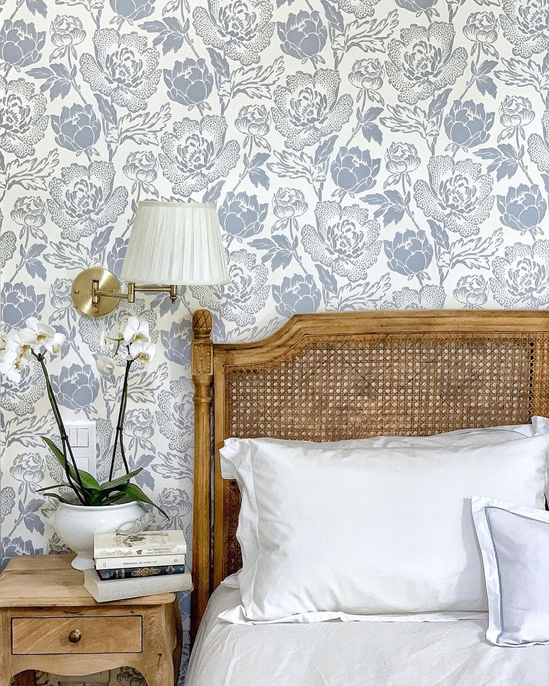 Blue floral wallpaper and cane headboard in French farmhouse bedroom by Vivi et Margot.