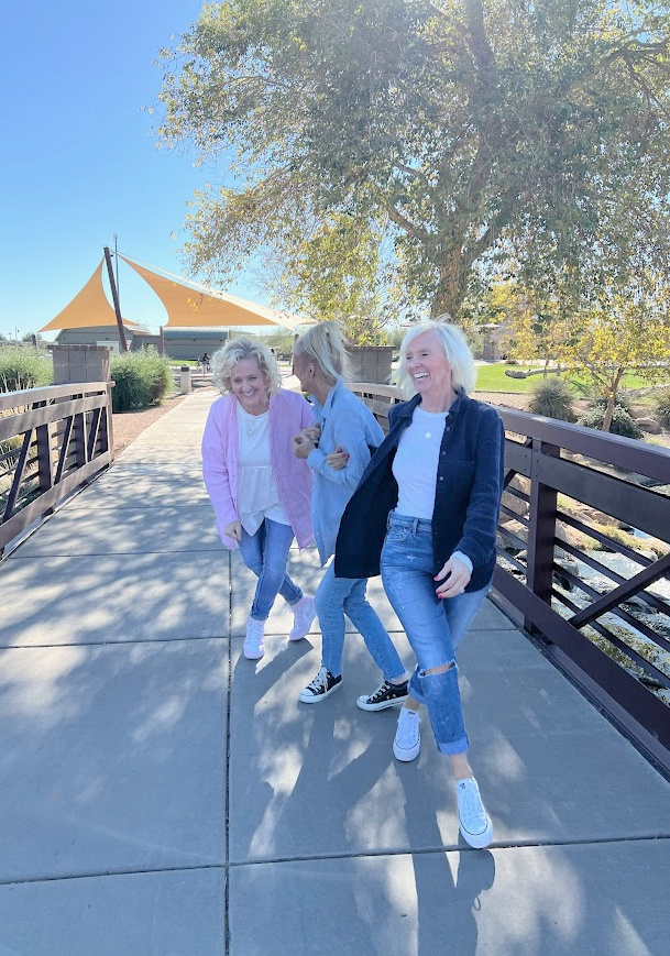 Michele of Hello Lovely Studio with her sisters, laughing on a bridge.