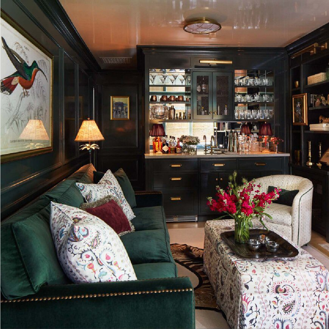 Chic bar area with velvet sofa, swivel chair, wall panels, moody color and lacquered ceiling - interior design by Brittany Bromley.
