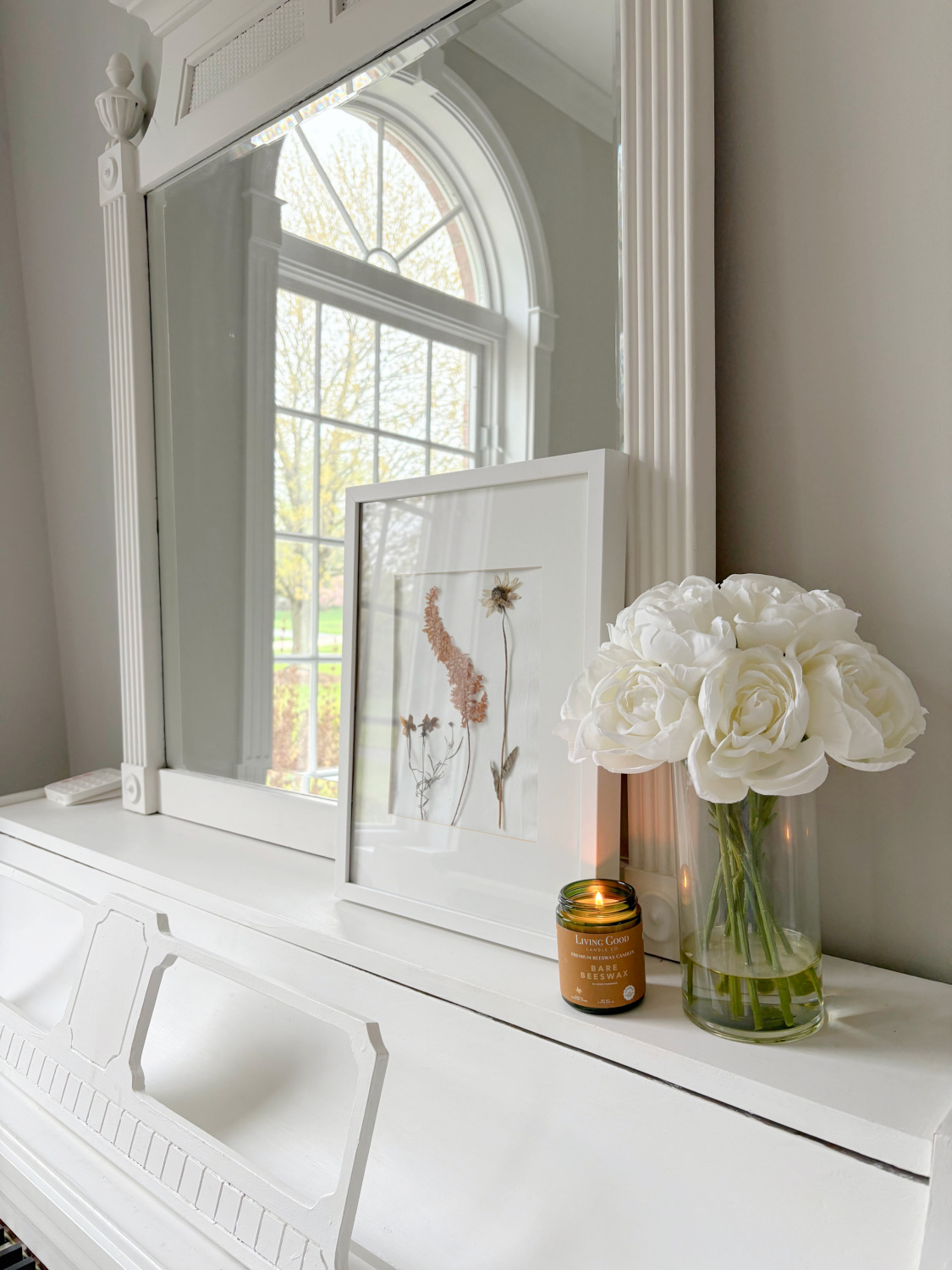 Hello Lovely's music room with handmade herbarium and Living Good Candle Co Bare Beeswax candle on white piano.