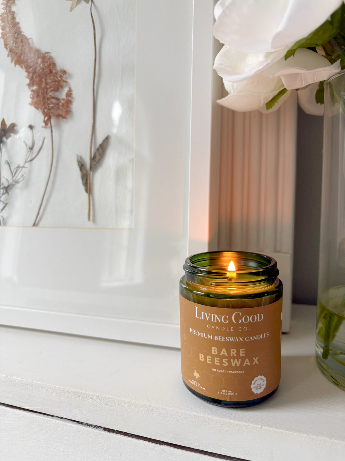 Hello Lovely's music room with handmade herbarium and Living Good Candle Co Bare Beeswax candle on white piano.