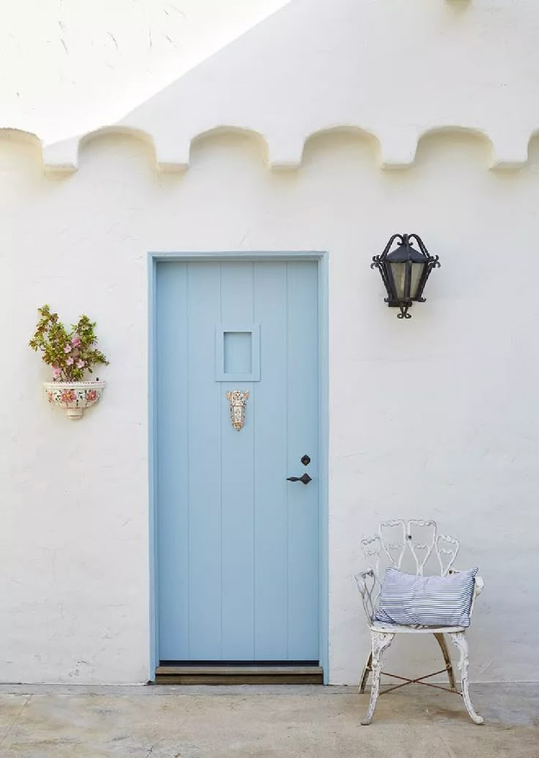 Scallop design on white stucco coastal cottage with cool blue door - via Martha Stewart.