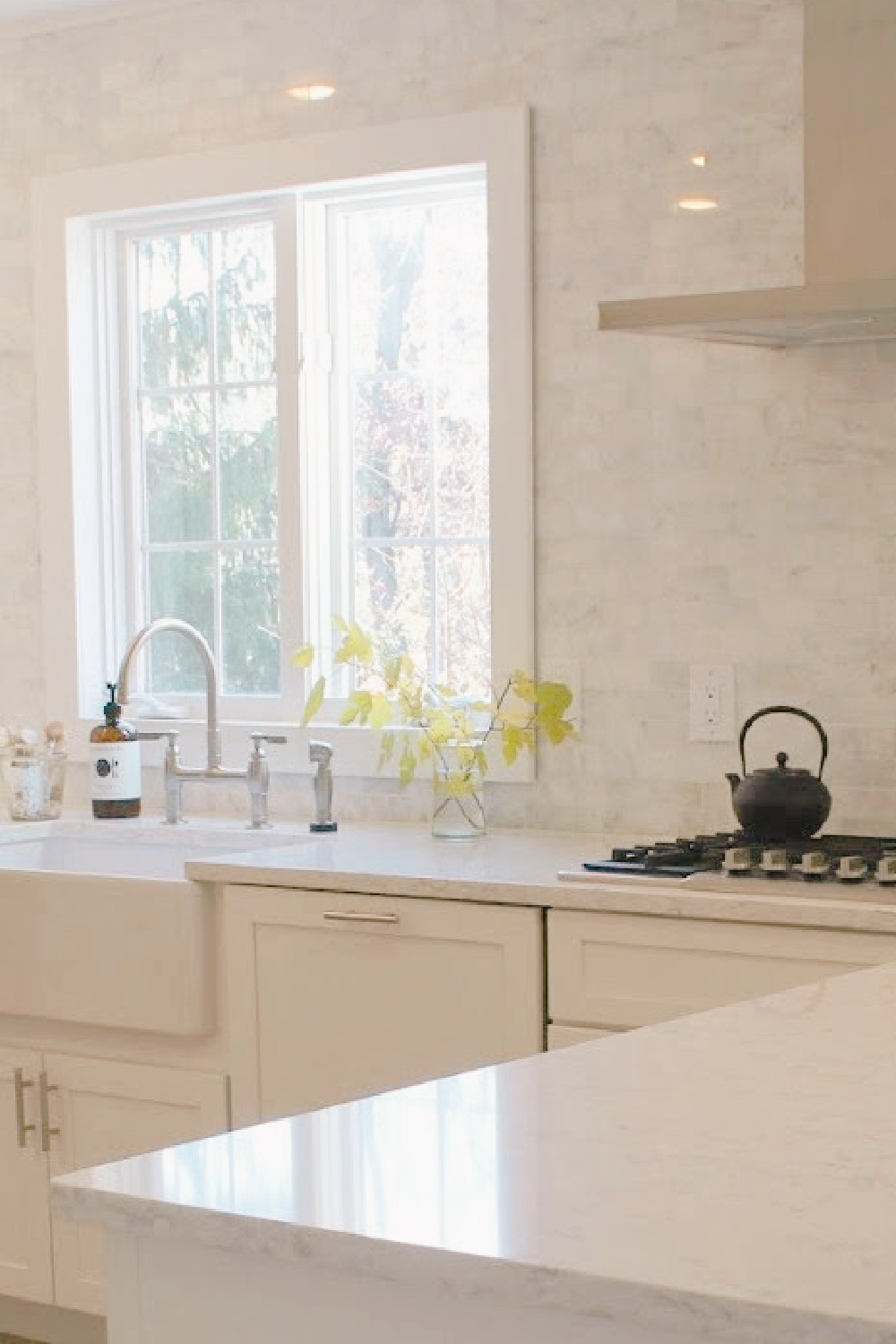Hello Lovely's serene kitchen with polished Venatino marble backsplash, farm sink, and Viatera SOPRANO white quartz.