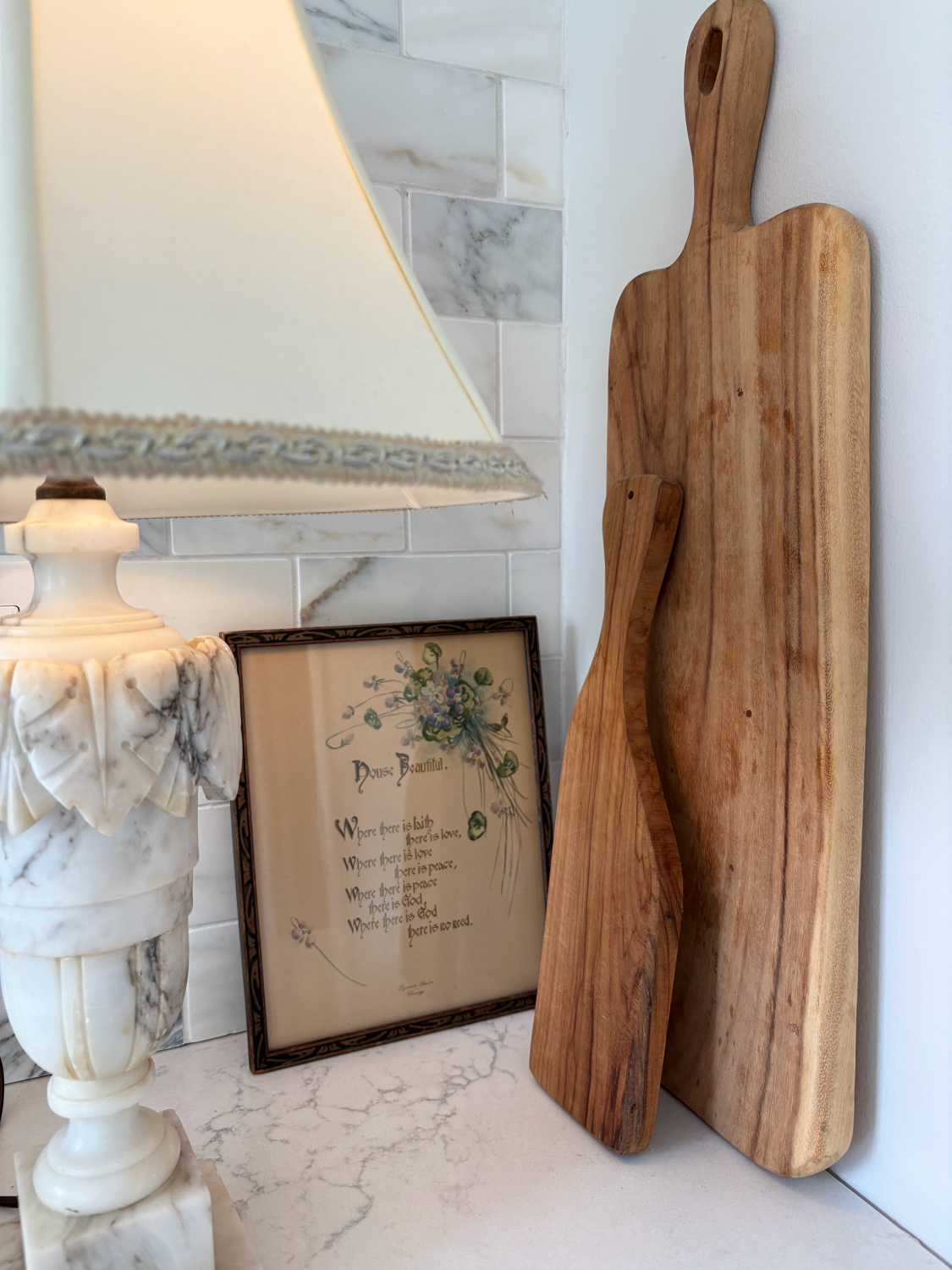Hello Lovely's kitchen counter with vintage Italian marble lamp, framed print, and cutting boards. Countertop is Viatera Muse and backsplash is calacatta gold marble subway tile.