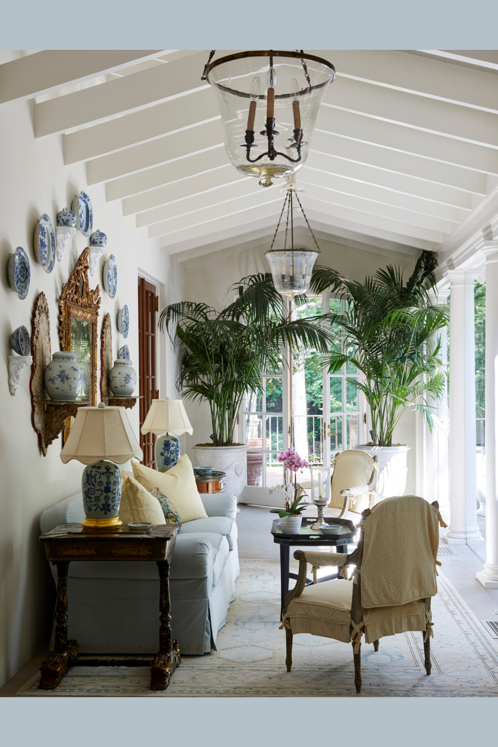 Loggia with blue plates on wall, palms, and elegance in Cathy Kincaid designed interior at a Highland Park Beaux Arts home.