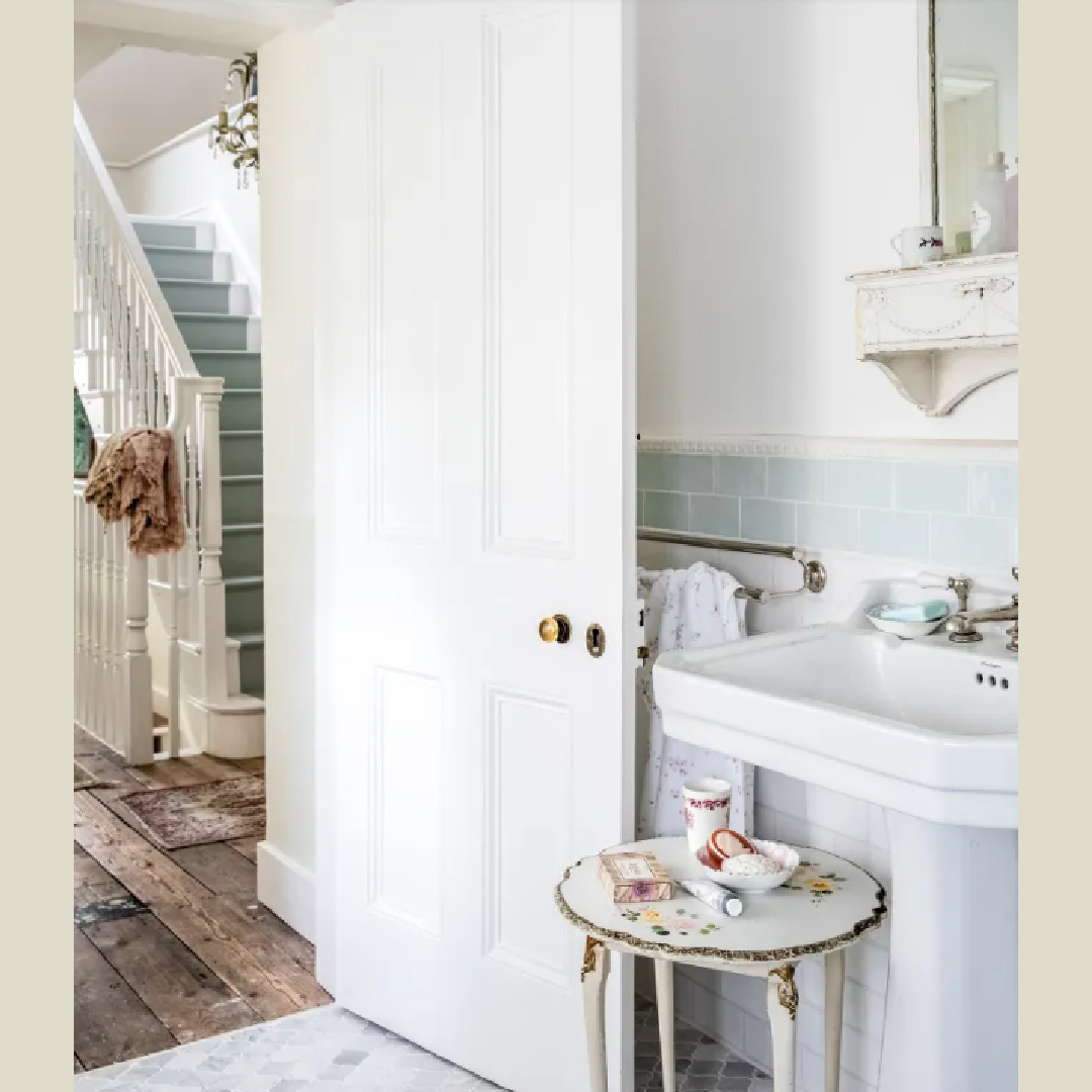 Bath with light blue subway tile and view of staircase with blue painted stair runner - in Rachel Ashwell's MEADOW MANOR (CICO Books, 2026); photo by Amy Neunsinger.