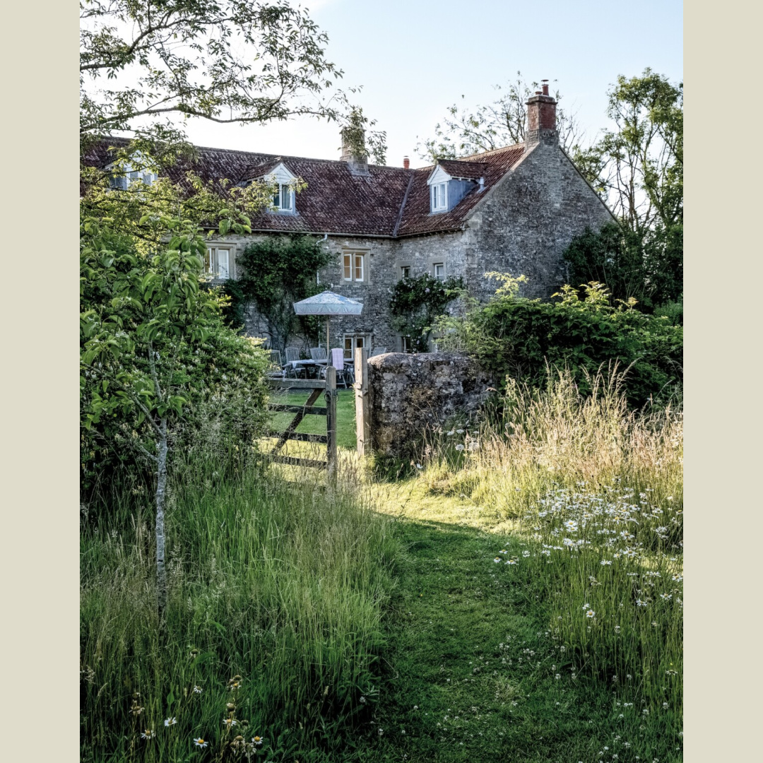 Garden with stone wall and gate of 17th century stone house in English countryside. Rachel Ashwell's Meadow Manor in Somerset, England. Photo: Amy Neunsinger.