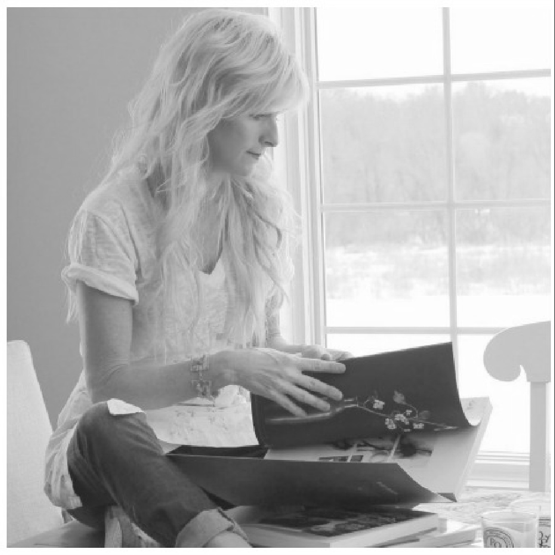 Michele of Hello Lovely reviewing books seated on kitchen table.